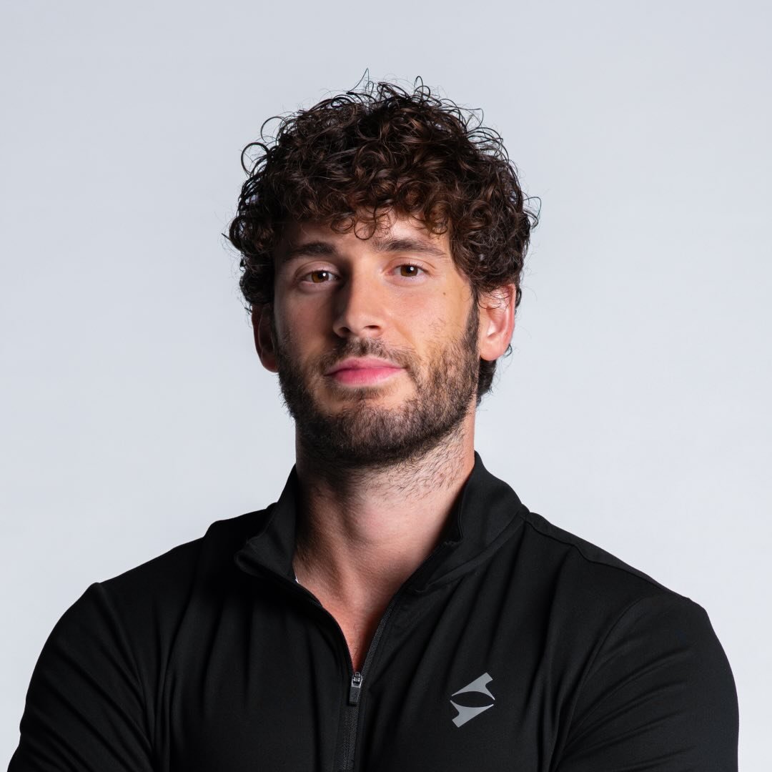 Elderly person gazes confidently to the side, wearing large, dangling earrings and a dark sweater, against a soft, neutral background. Serene and elegant tone.