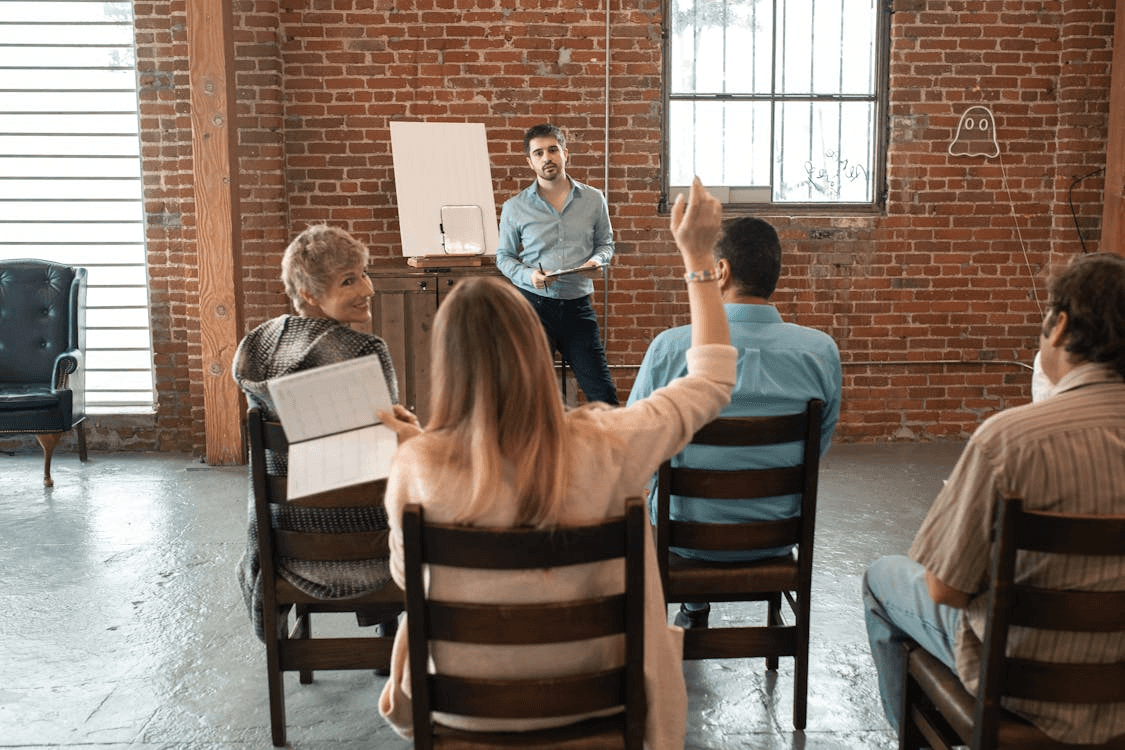 Woman Sitting at the Back of the class Raising her Hand