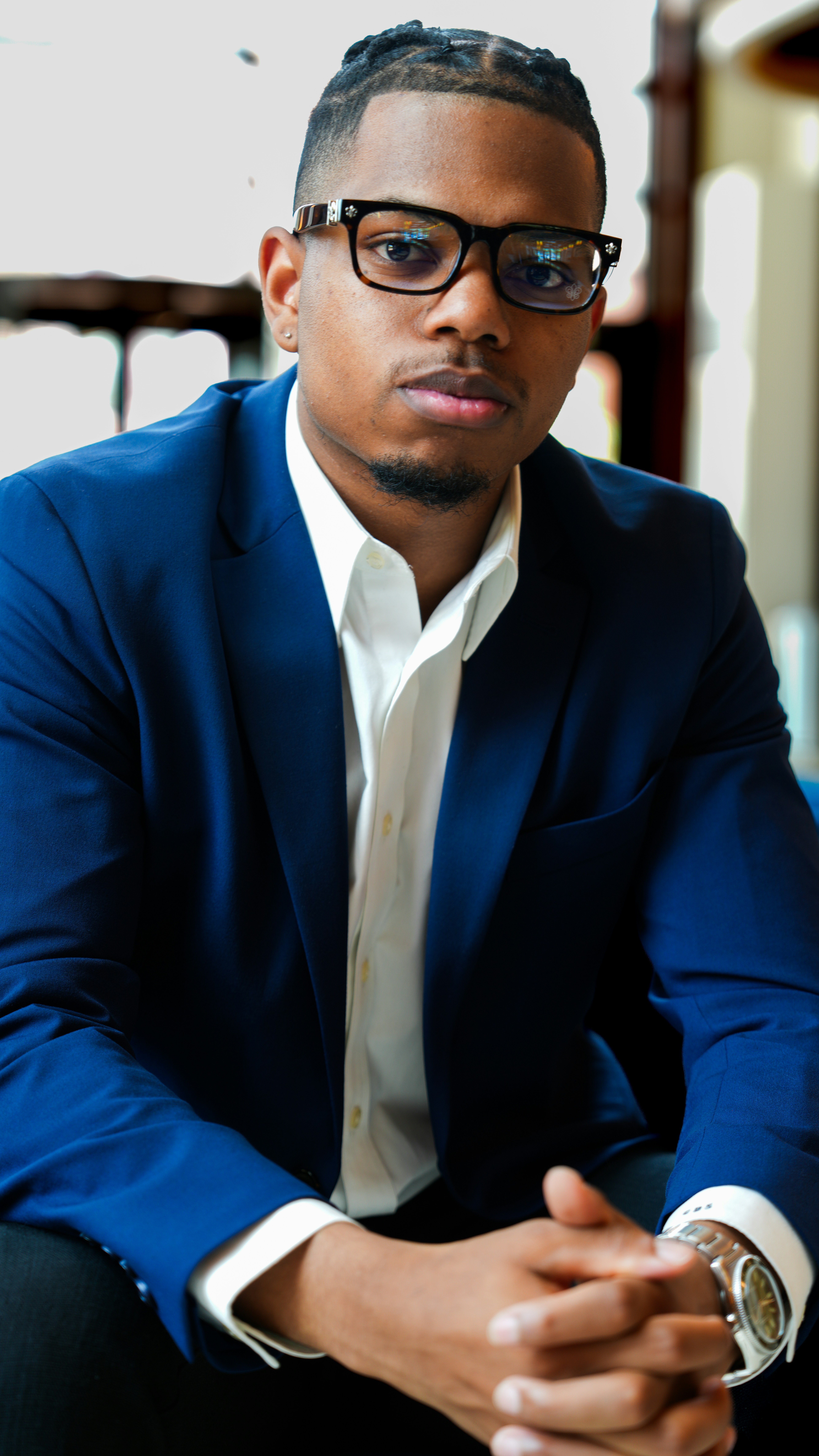 A man in a suit and glasses sitting down