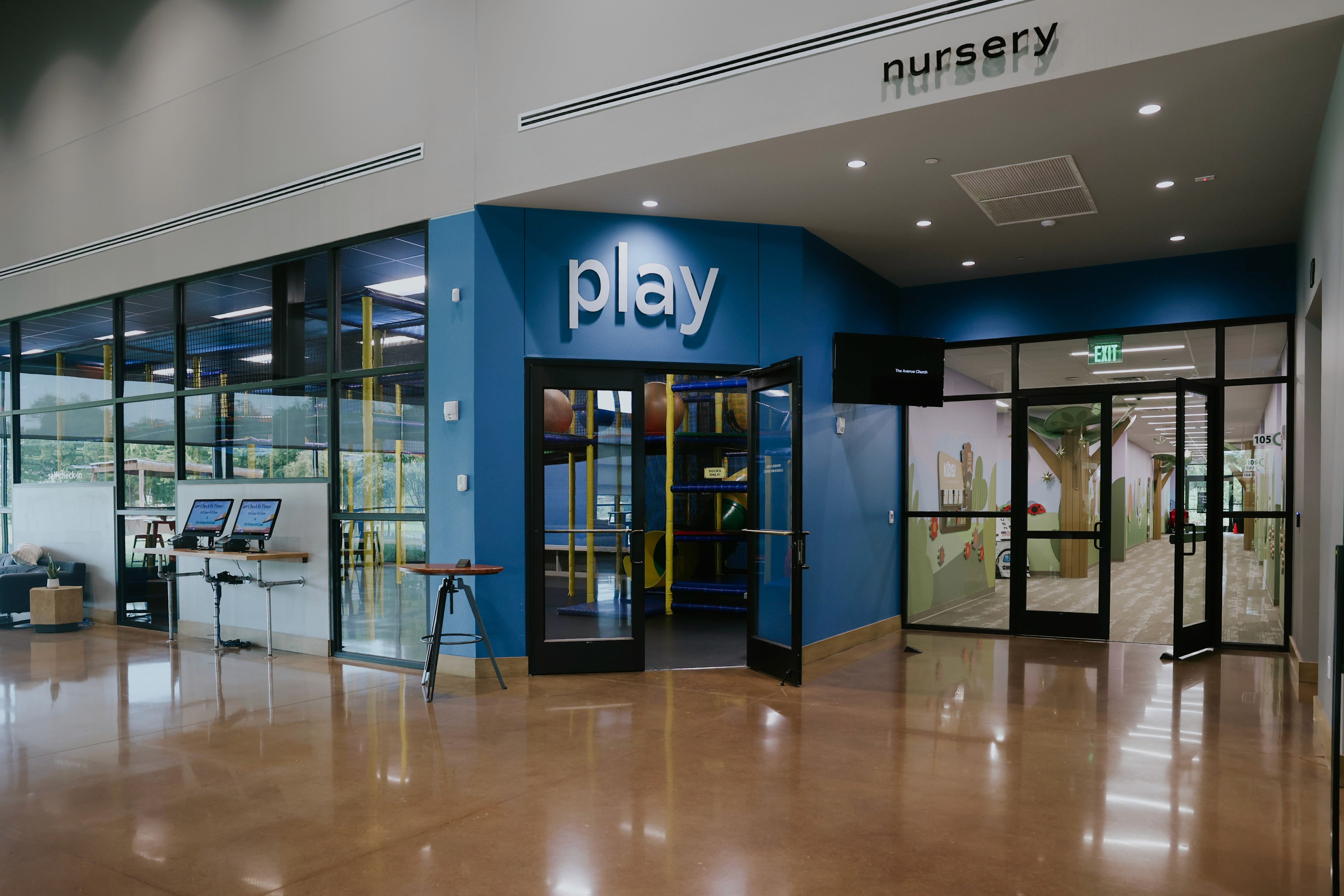 A busy indoor space with people walking, carrying bags, and interacting near a blue entrance.