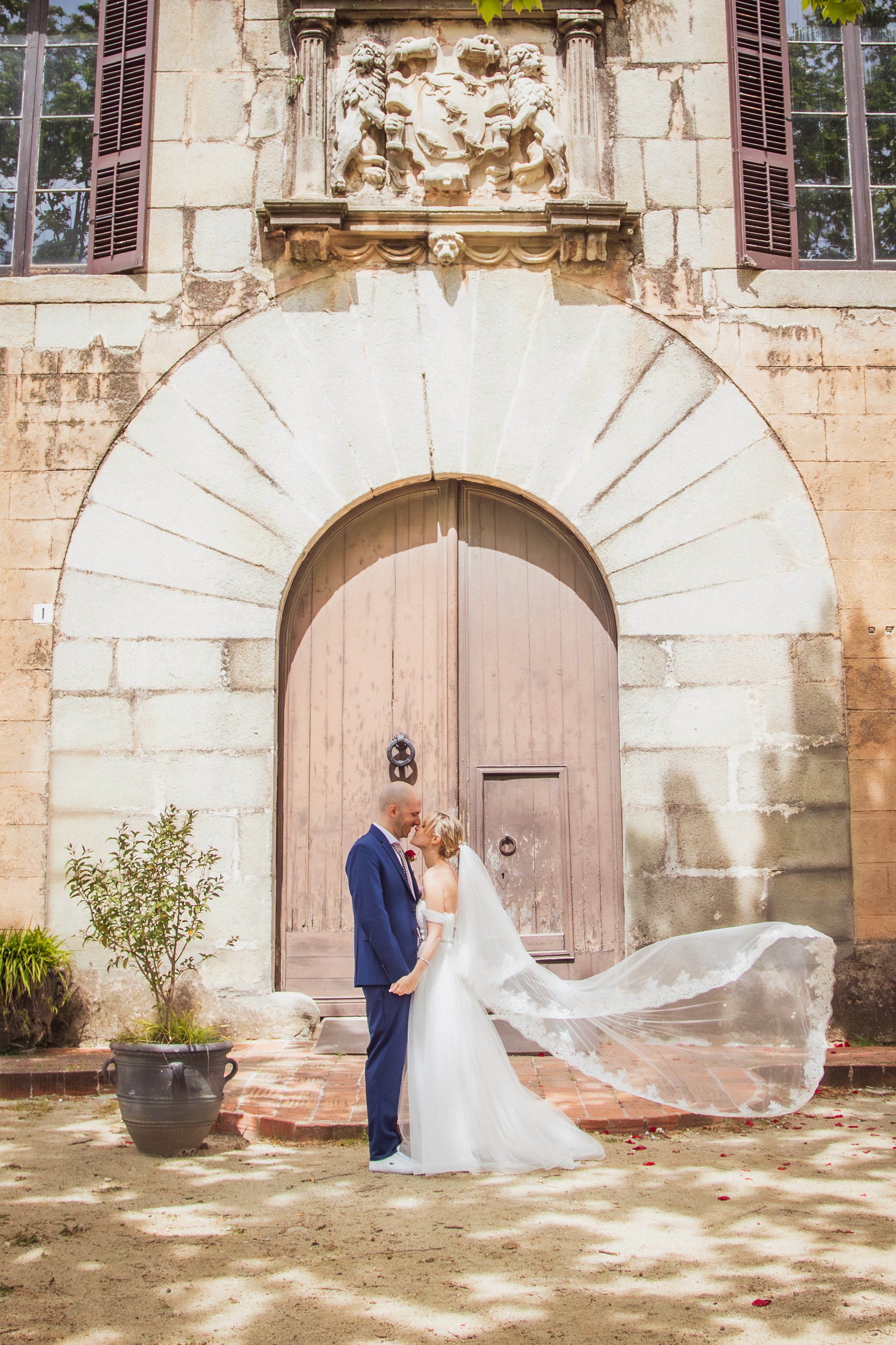Sesión de boda con el velo al viento delante de una puerta
