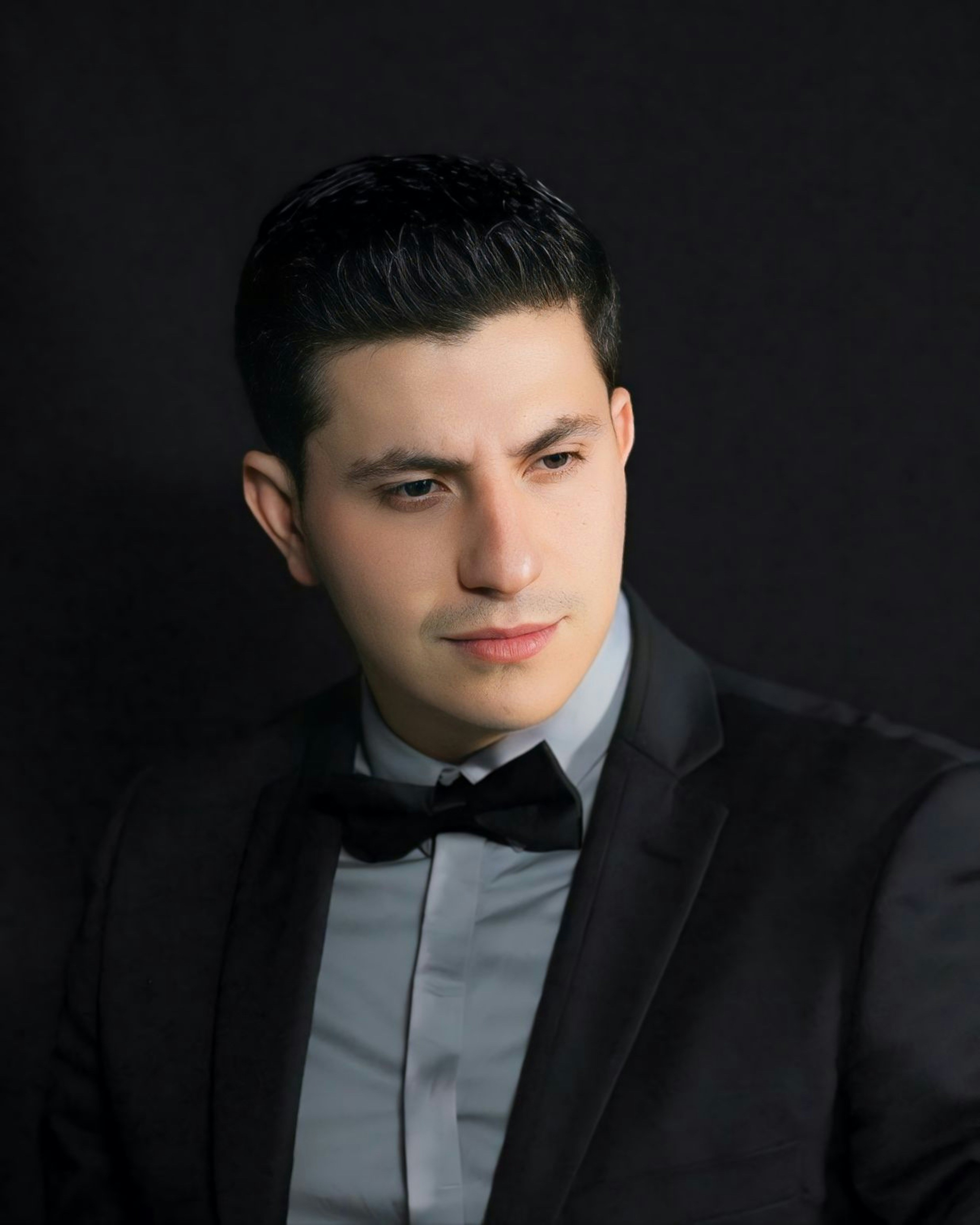 a man in a tuxedo poses for a picture