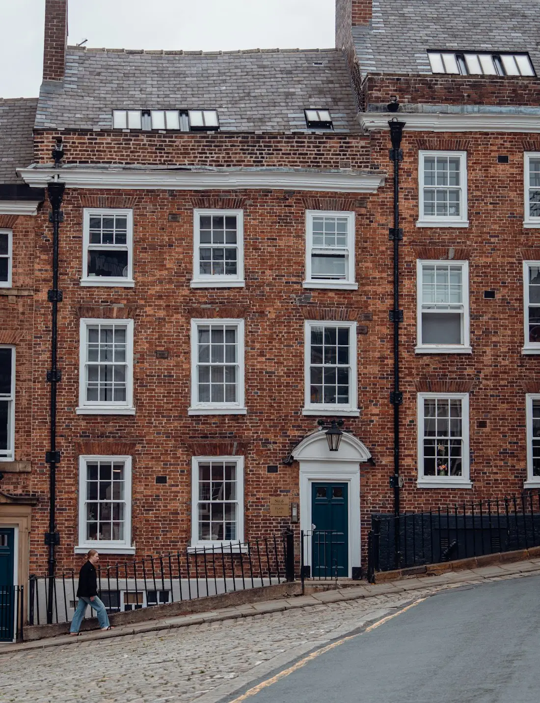 A red brick Georgian townhouse with white sash windows and a painted front door