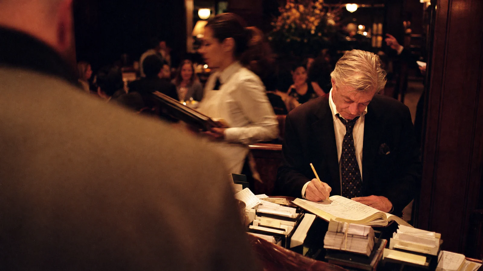 Maître annota il nome di un cliente abituale sul registro alla reception del ristorante
