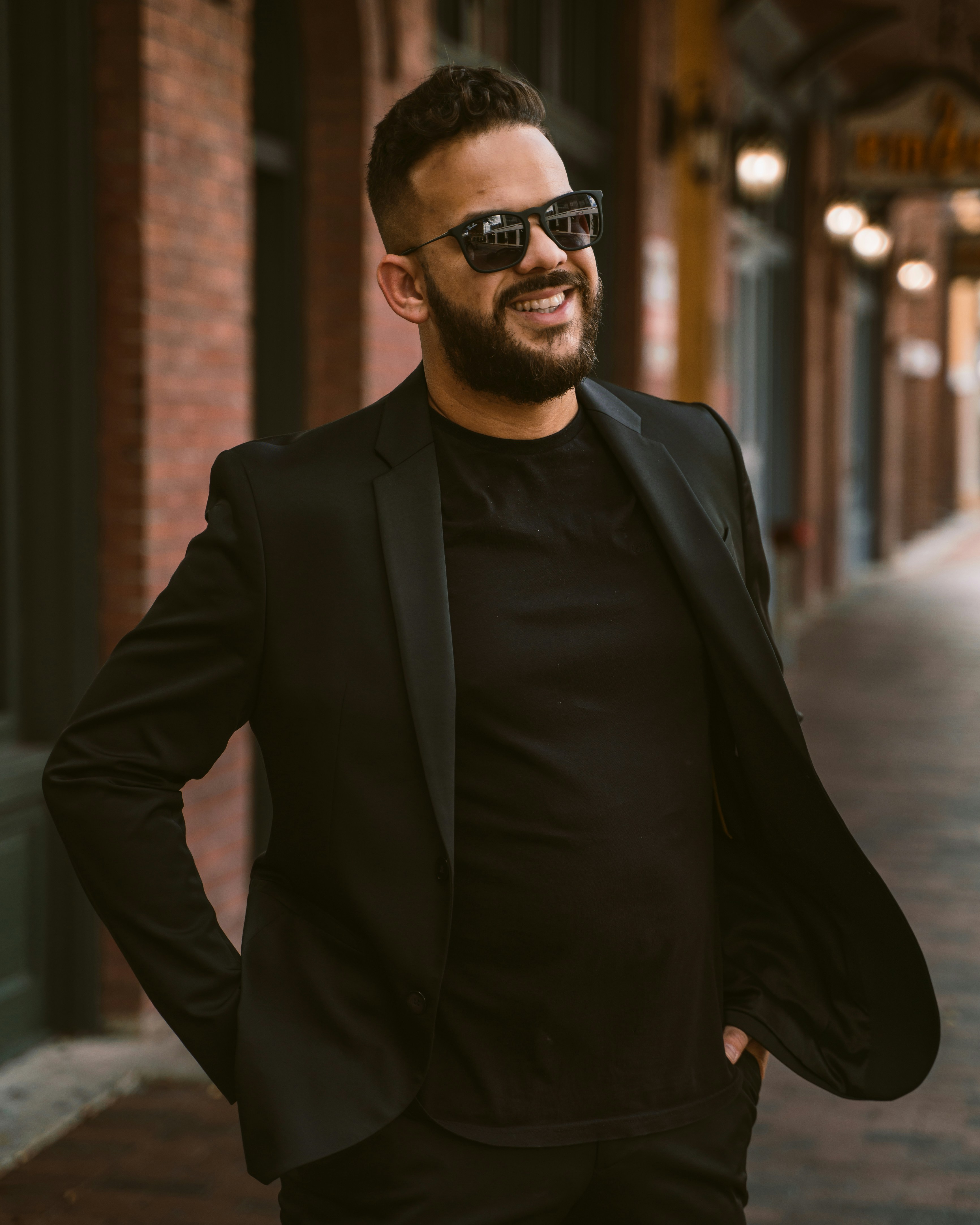 a man in a suit and sunglasses standing on a sidewalk