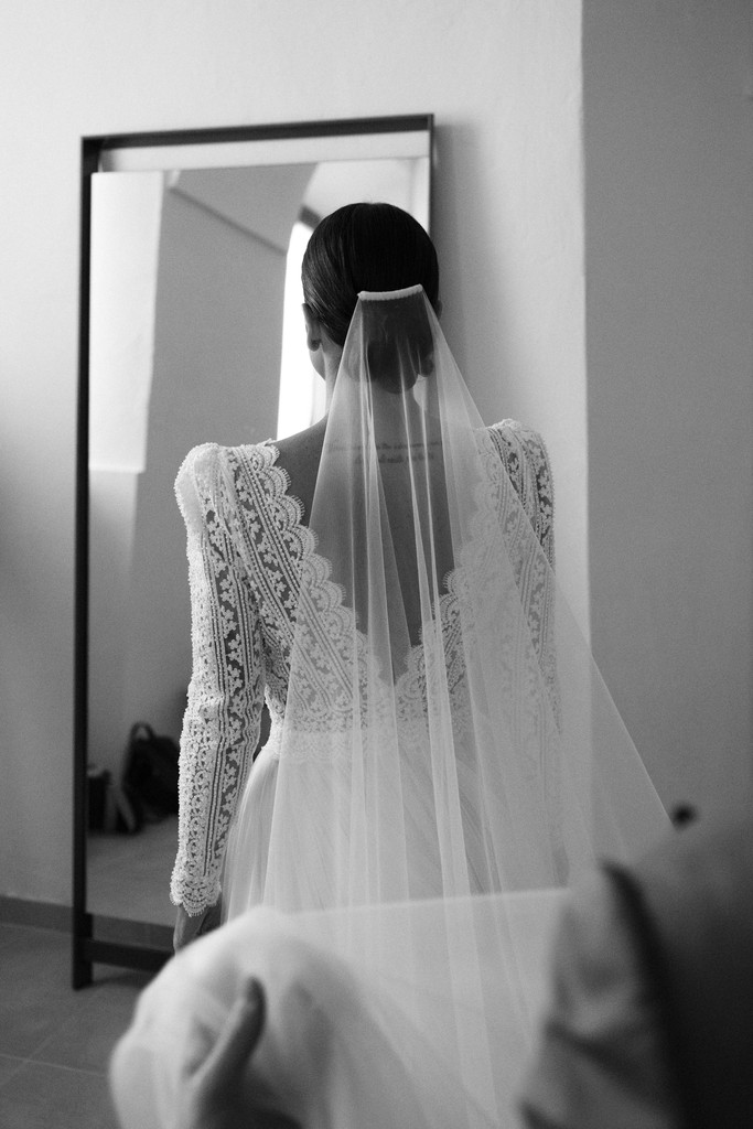 Sposa con velo lungo di spalle davanti a porta ad arco - matrimonio Rebecca e Giorgio a Villa La Favorita