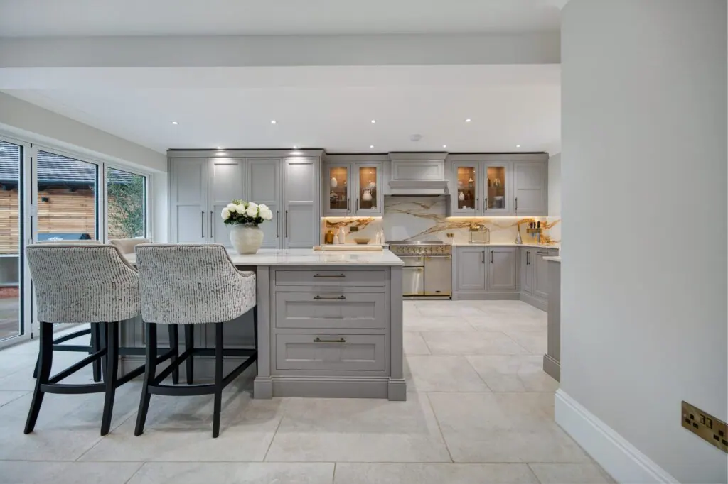 Green shaker kitchen with copper pendant lights and oak bar stools