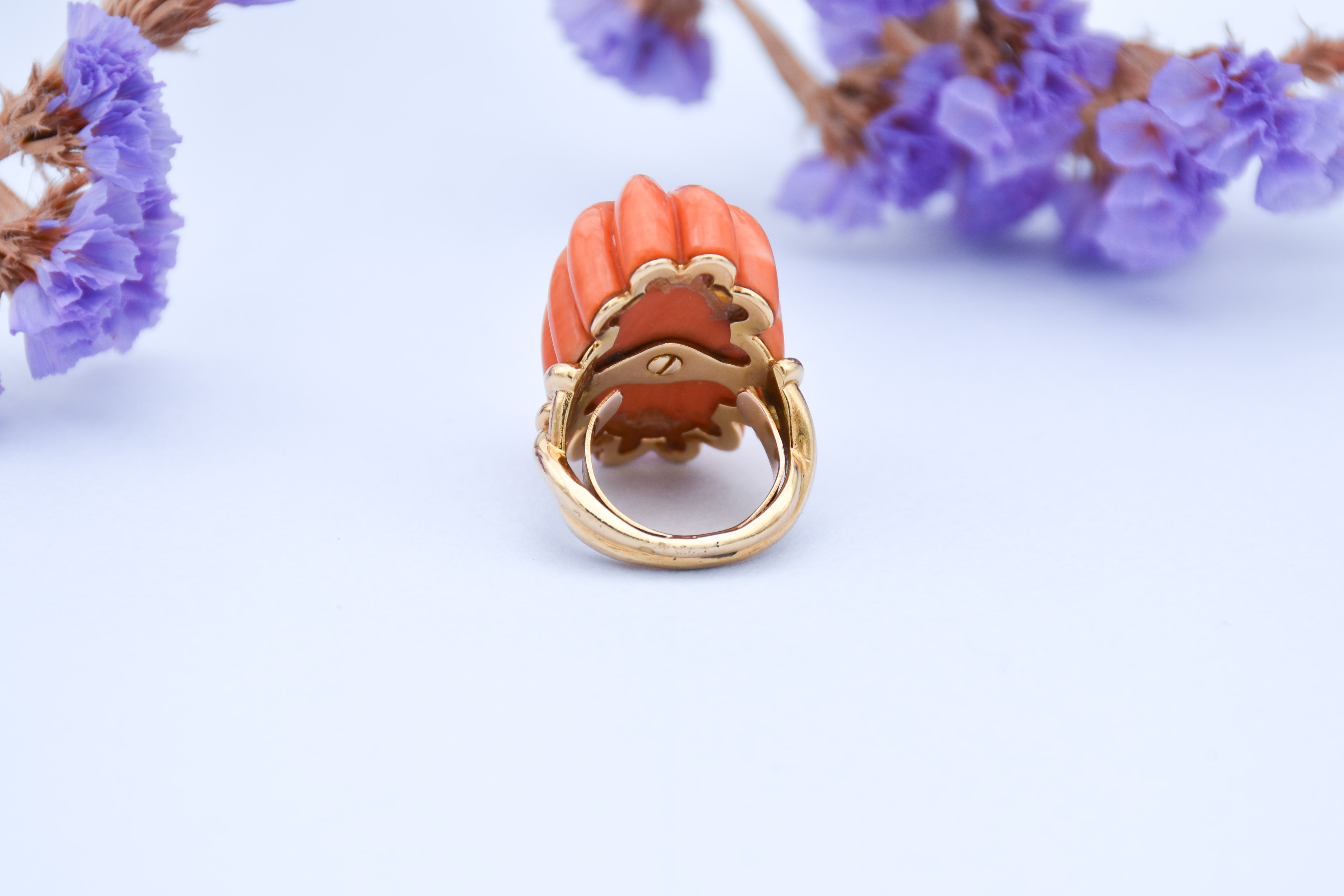 Vue de dos d'une bague Chaumet en corail en forme de fleur avec un petit cabochon d'onyx sur le dessus 