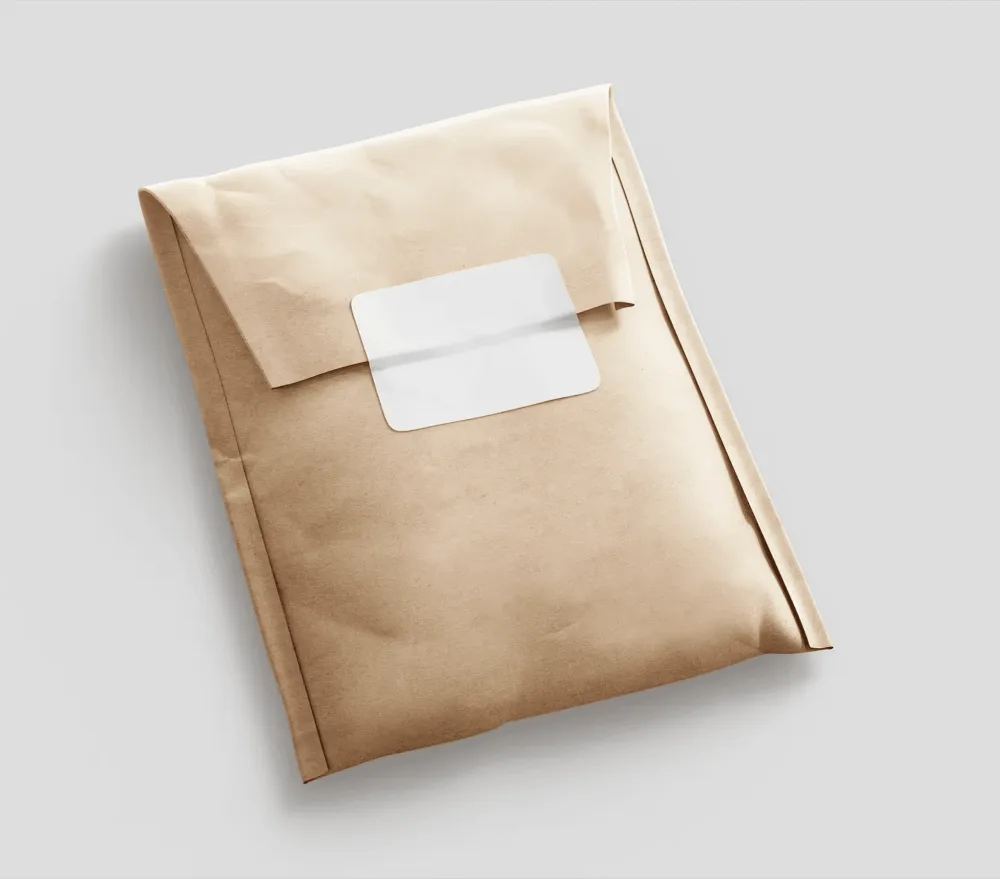A kraft paper package mockup with a folded closure and a minimalist white label, set against a black background. The natural texture and earthy tone highlight eco-friendly packaging design.