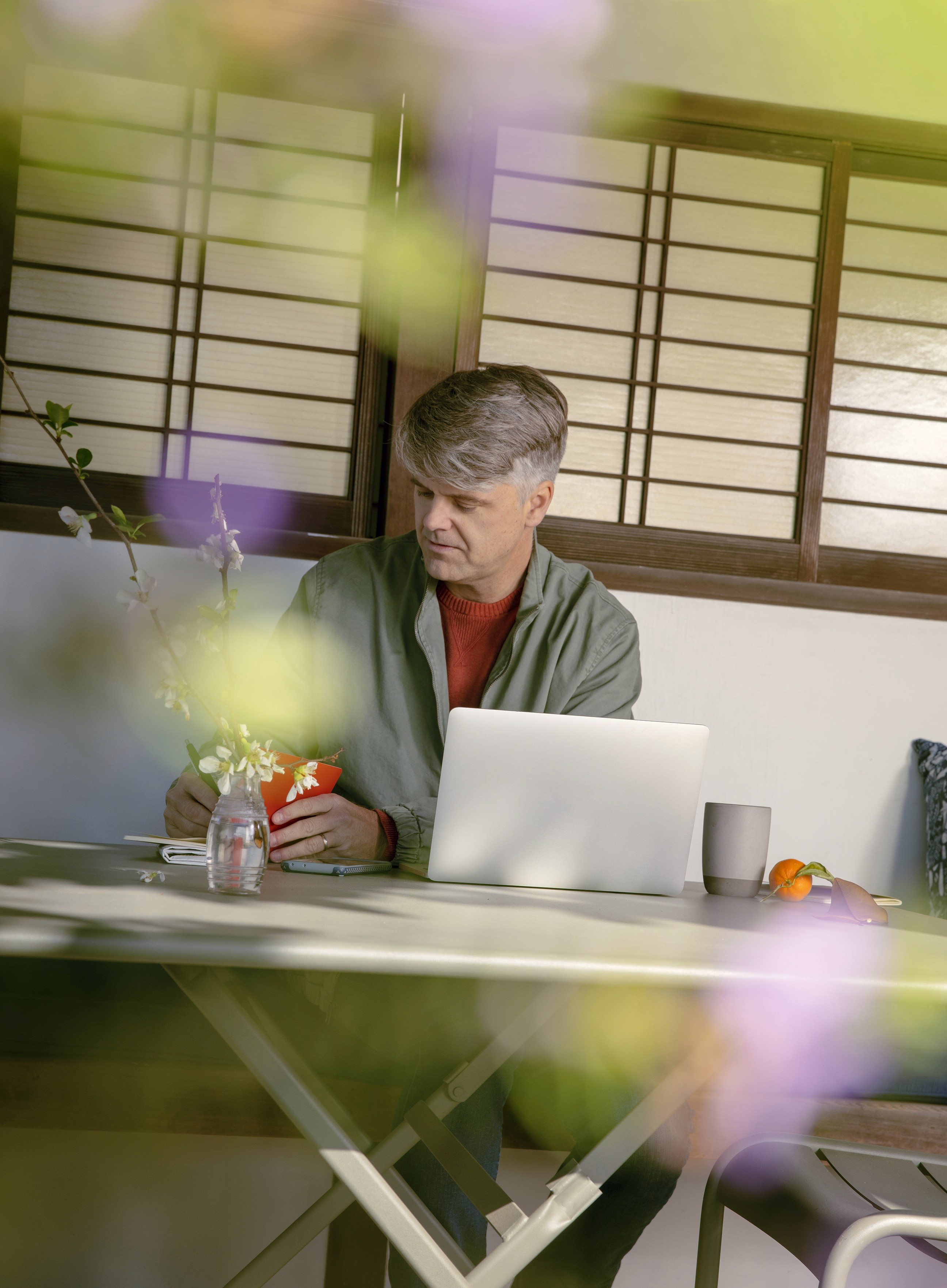 Portrait of a man working on a laptop in his backyard.