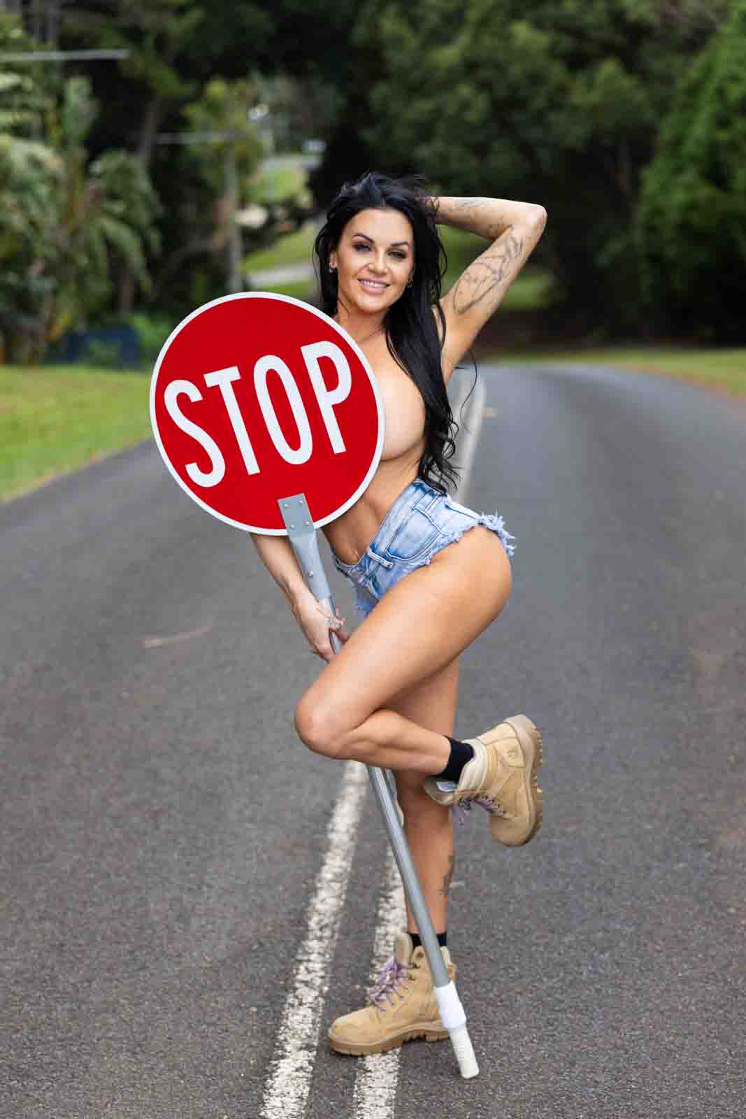 Young topless woman holding stop sign