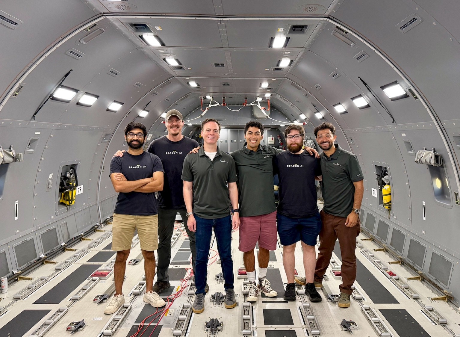 Six members of the Beacon AI team standing inside an aircraft's empty cargo cabin