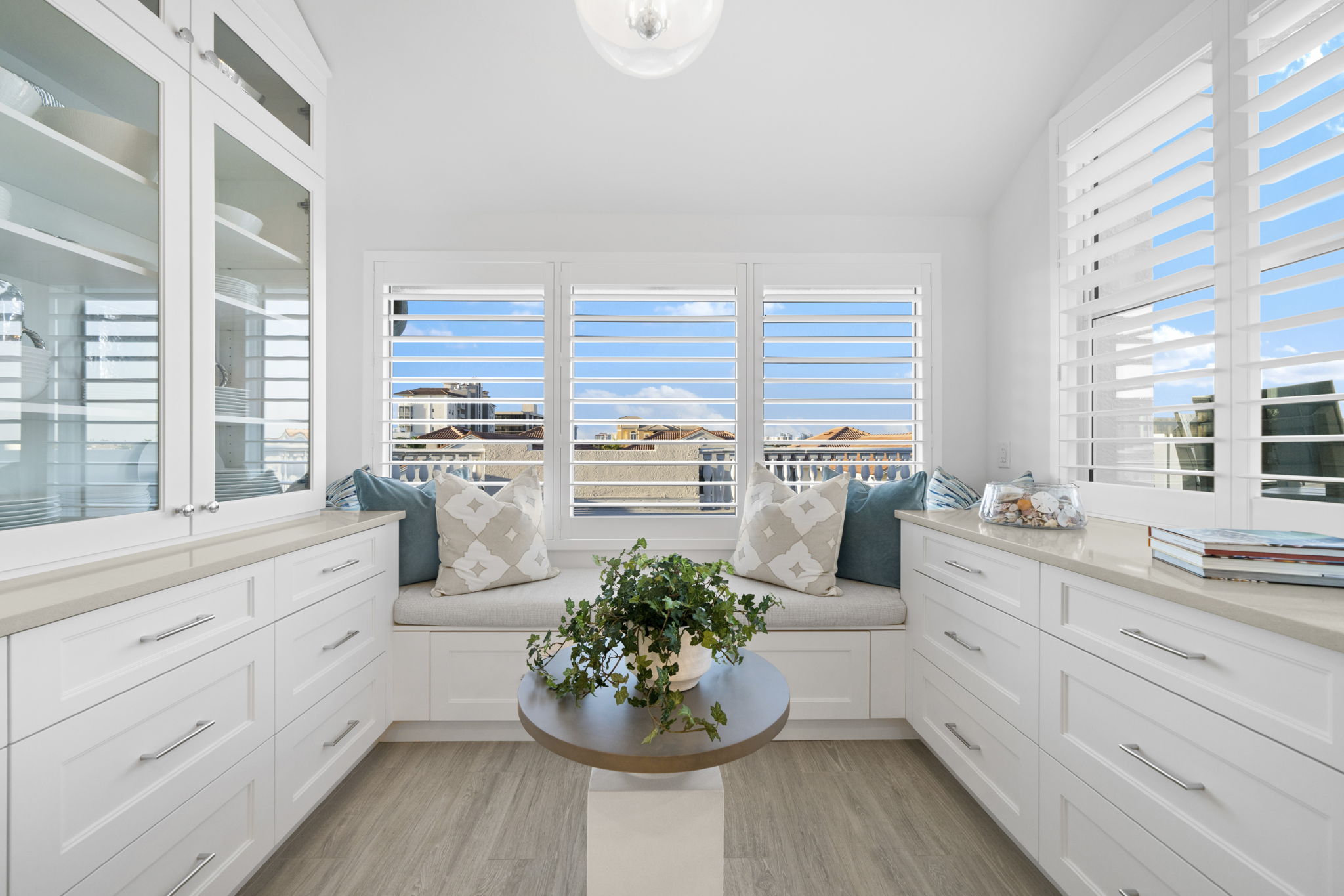 a small lounge area surrounded by windows with white wooden shutters