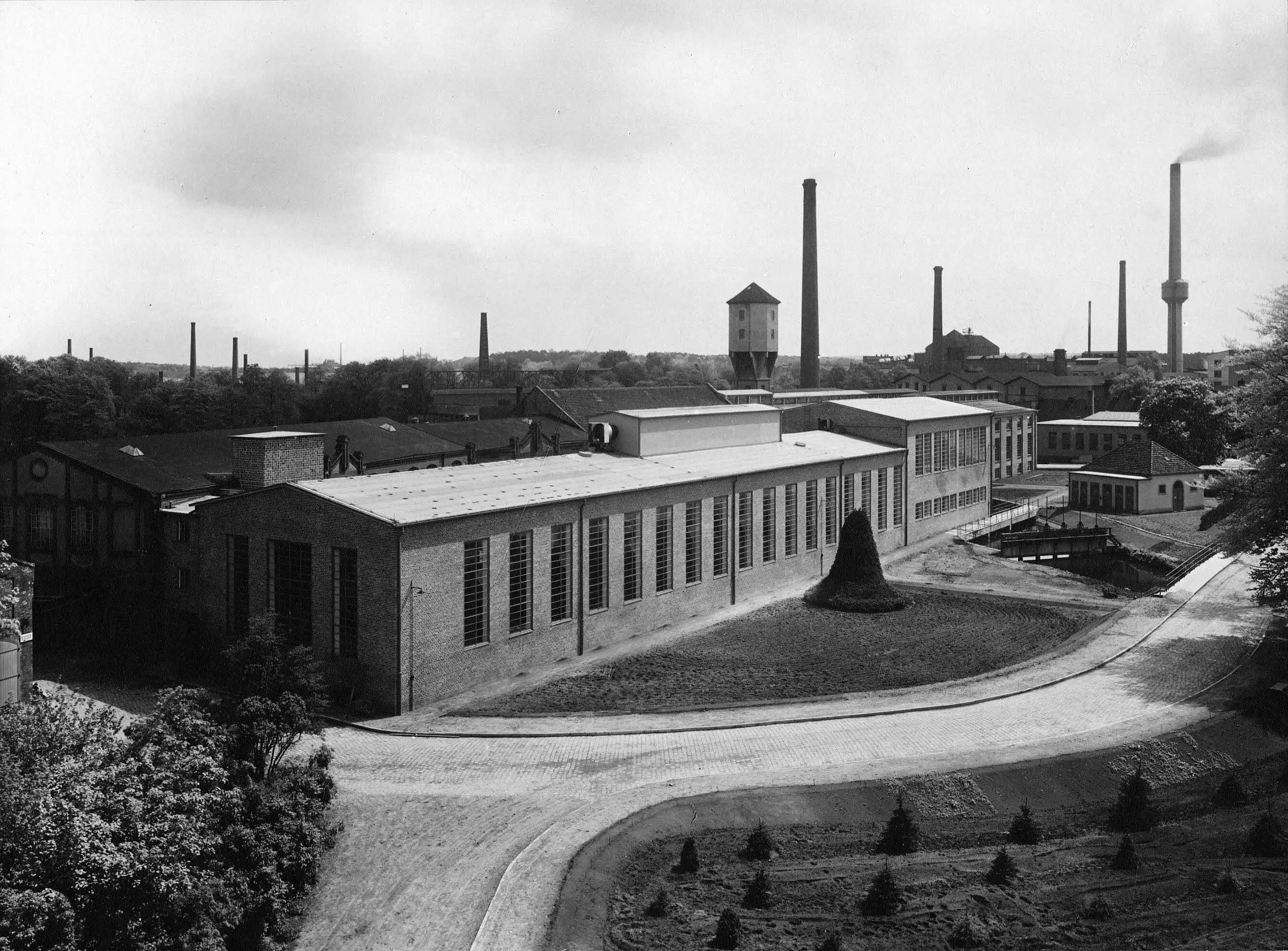 Historisches Foto (1929-1938) von der Fabrikantenvilla mit Blick auf die Hertlein-Halle, das weitere Hallenensemble, den Wasserturm und das Büttengebäude auf dem Gelände der Papierfabrik Wolfswinkel in Eberswalde