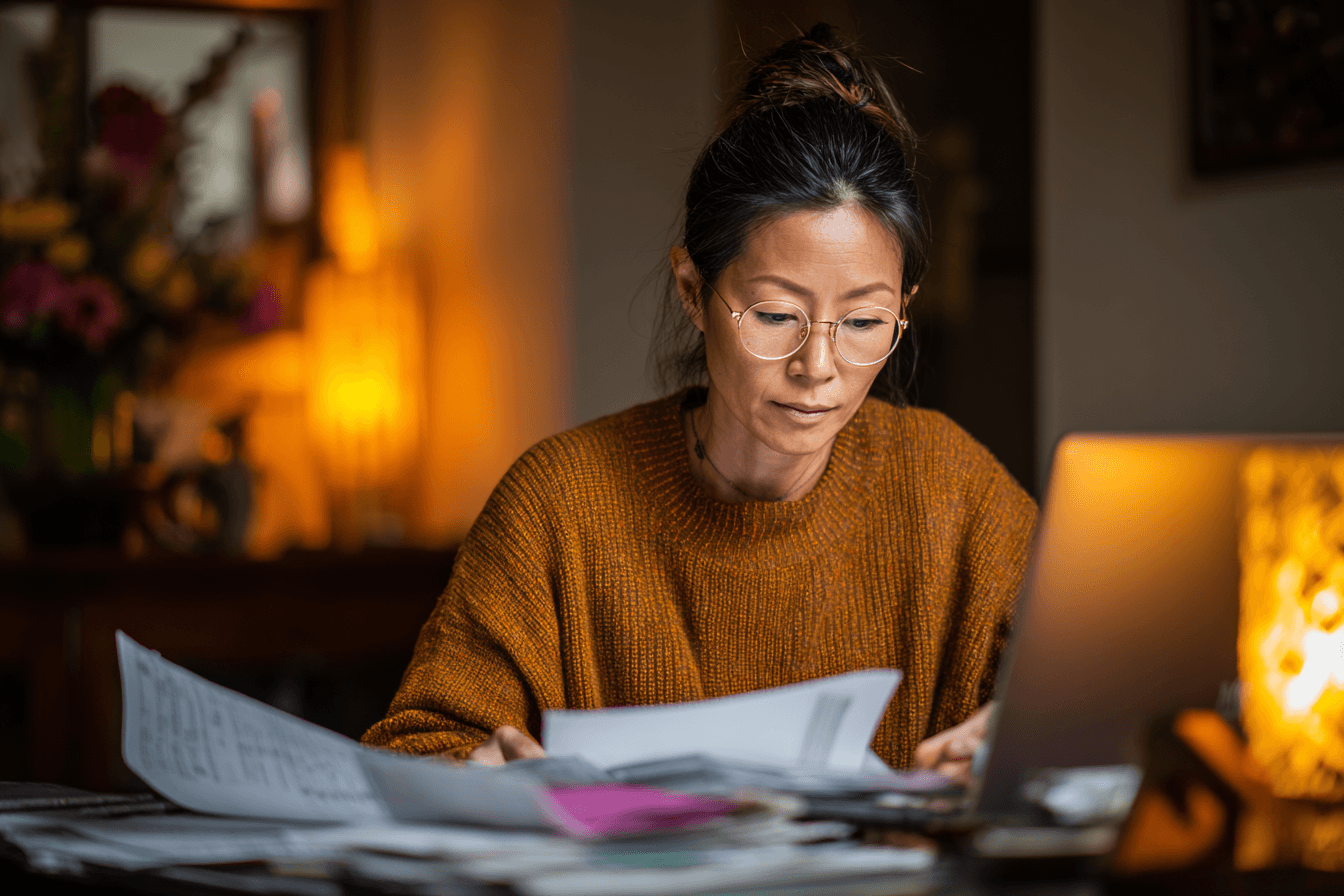 A home care agency owner, reviewing spreadsheets on her laptop at her desk in her office.