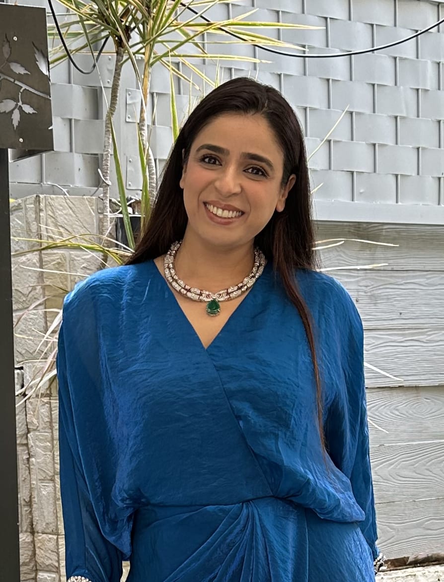 A person with shoulder-length blonde hair wearing a black newsboy cap and a black sweater.