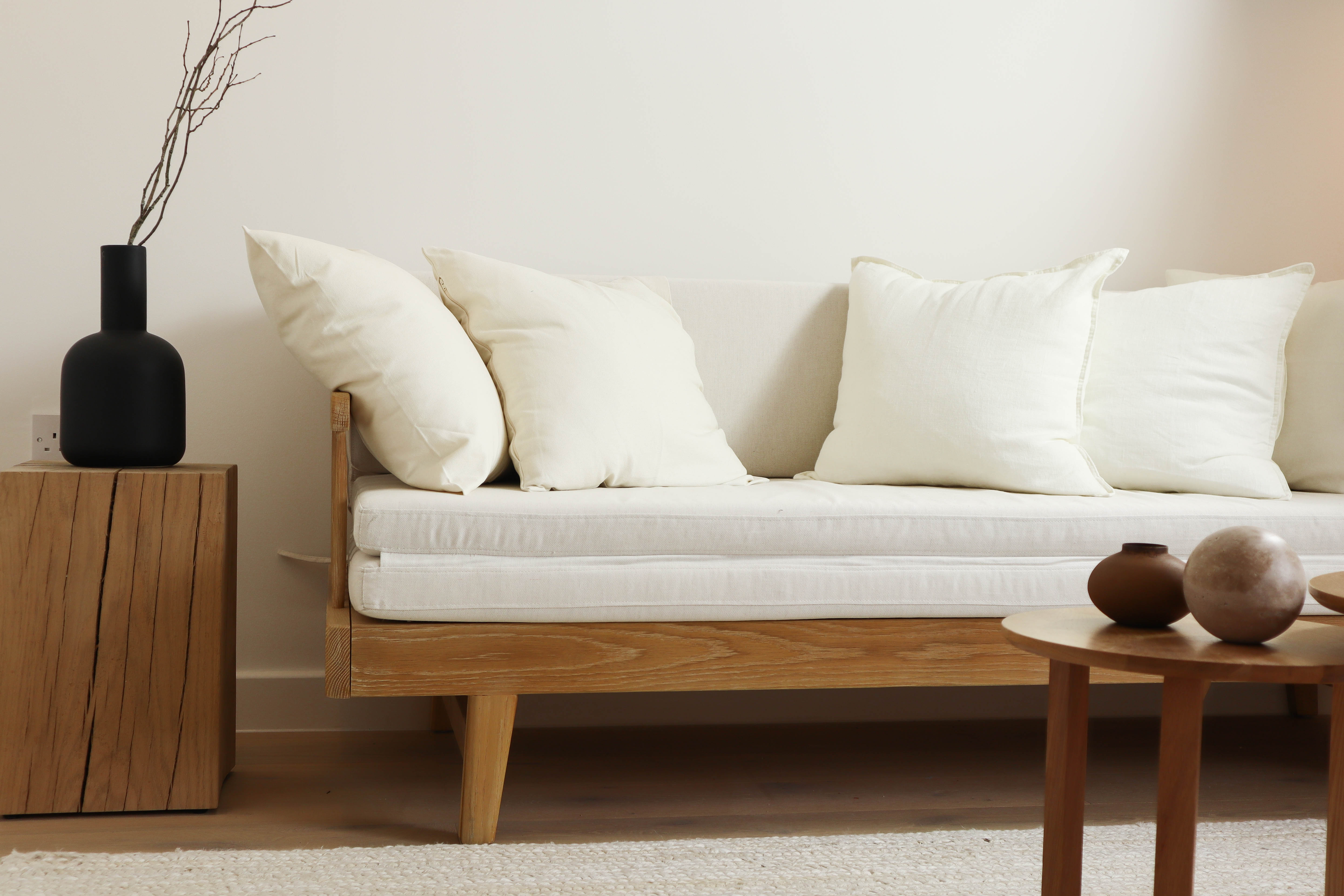 Minimalist nordic-inspired white couch with black vase on a side table