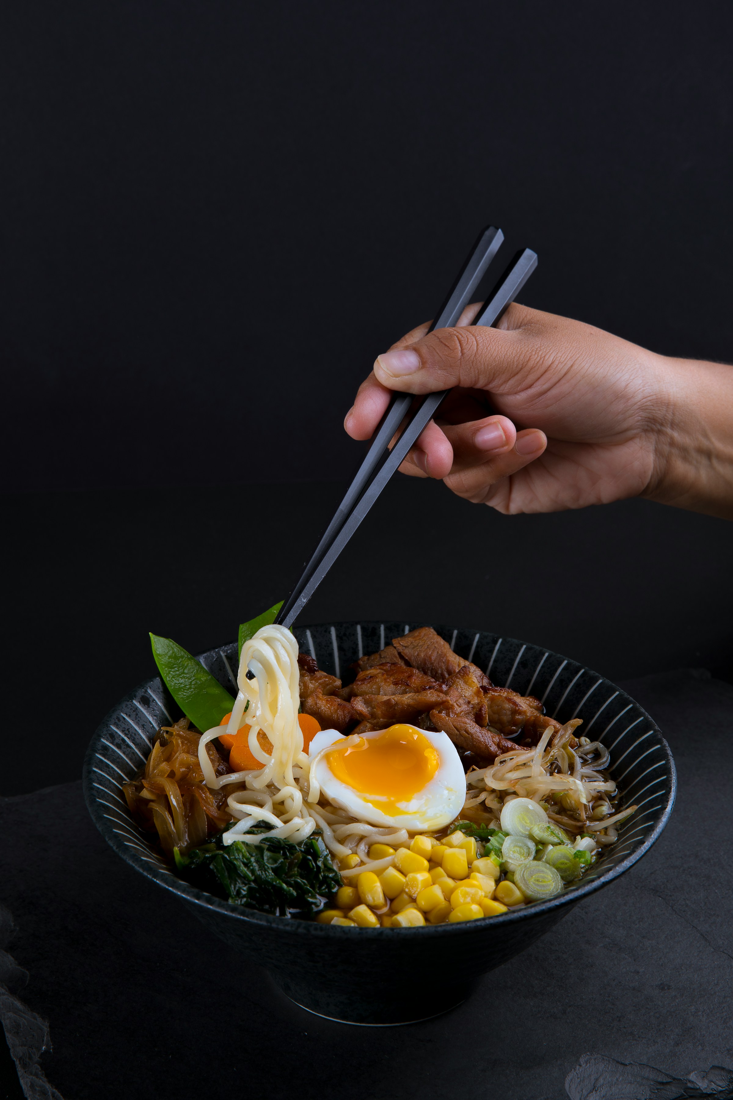 Ramen noodles lifted from the bowl with chopsticks