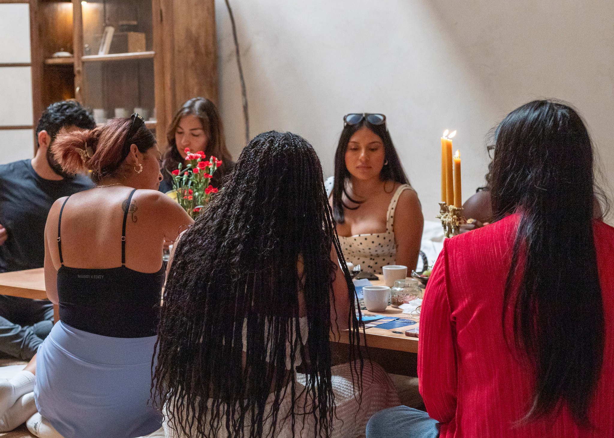 People gathered around a table with candles on it writing 