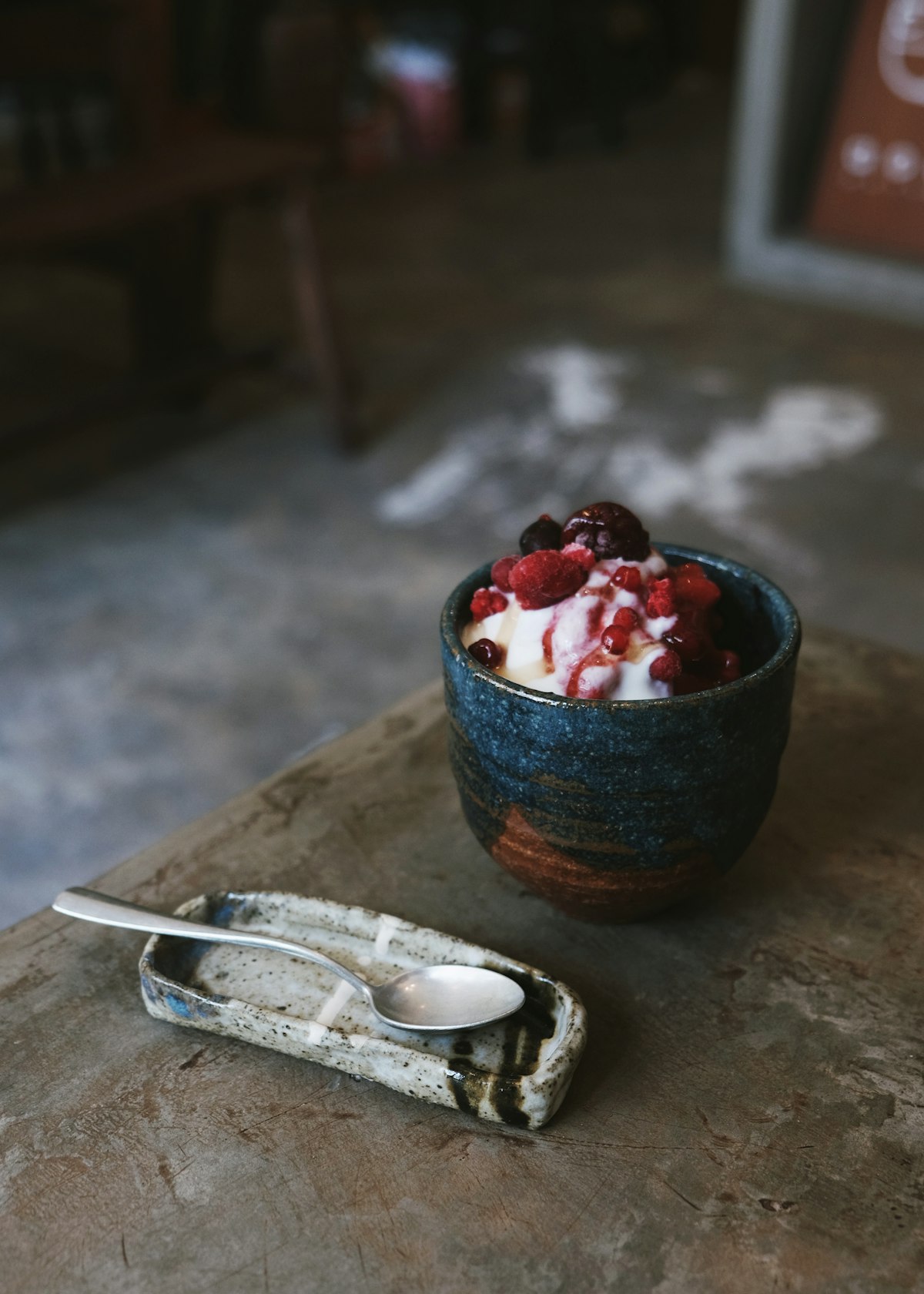 Cuenco de cerámica con helado y frutos rojos sobre una mesa de piedra