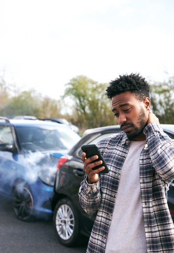 hombre sosteniendo el teléfono y el cuello después de ser chocado por detrás