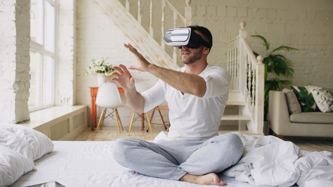 Man wearing vr headset sitting on bed gesturing on bed