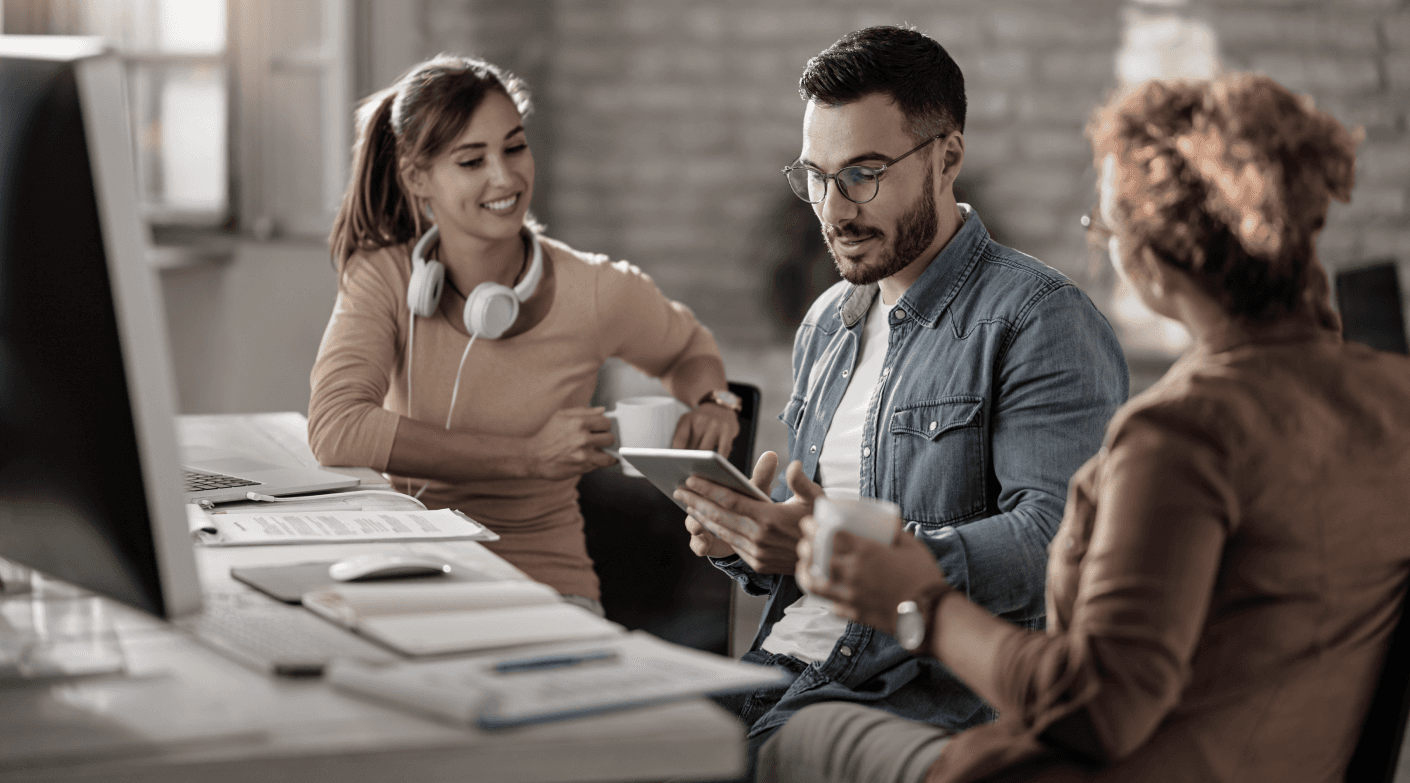 Black and white image of people working at a table with laptops, showing hands gesturing during discussion of digital content displayed on screens, with fabrica® logo in the corner.