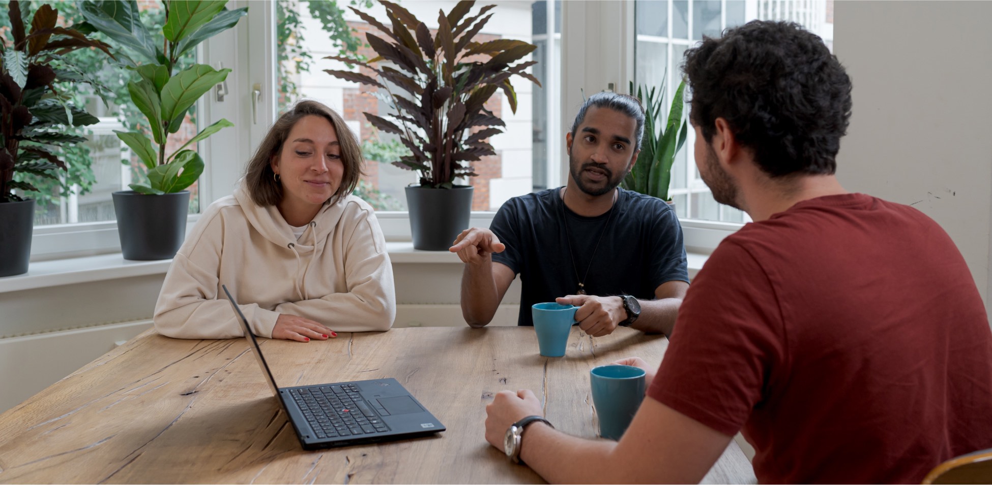 Some people having a discussion at an open table with plants.