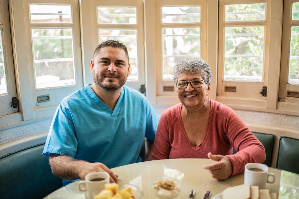 Male nurse and memory care resident at dining table