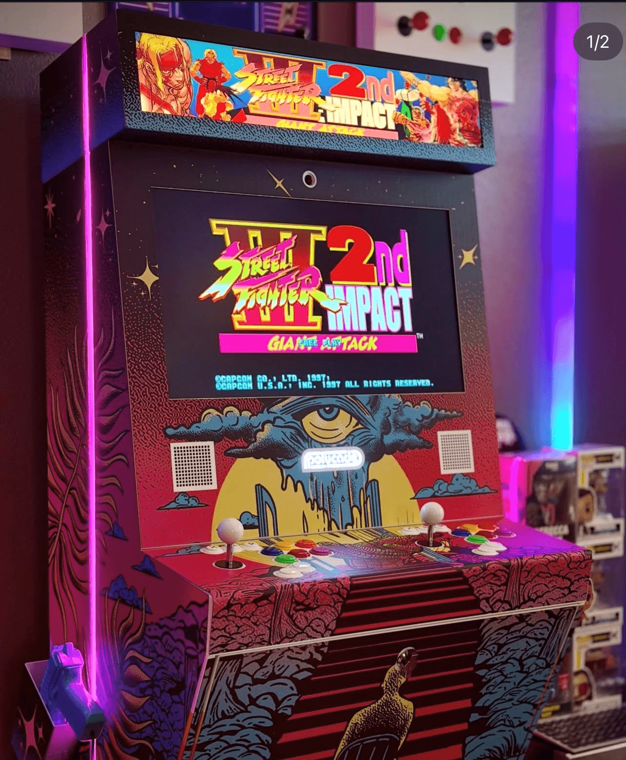 Street Fighter 2nd Impact arcade machine with colorful graphics, two joysticks, and buttons, featuring the game's logo and title "Giant Attack" on the screen, with a vibrant purple light strip on the side and decorative artwork on the cabinet.