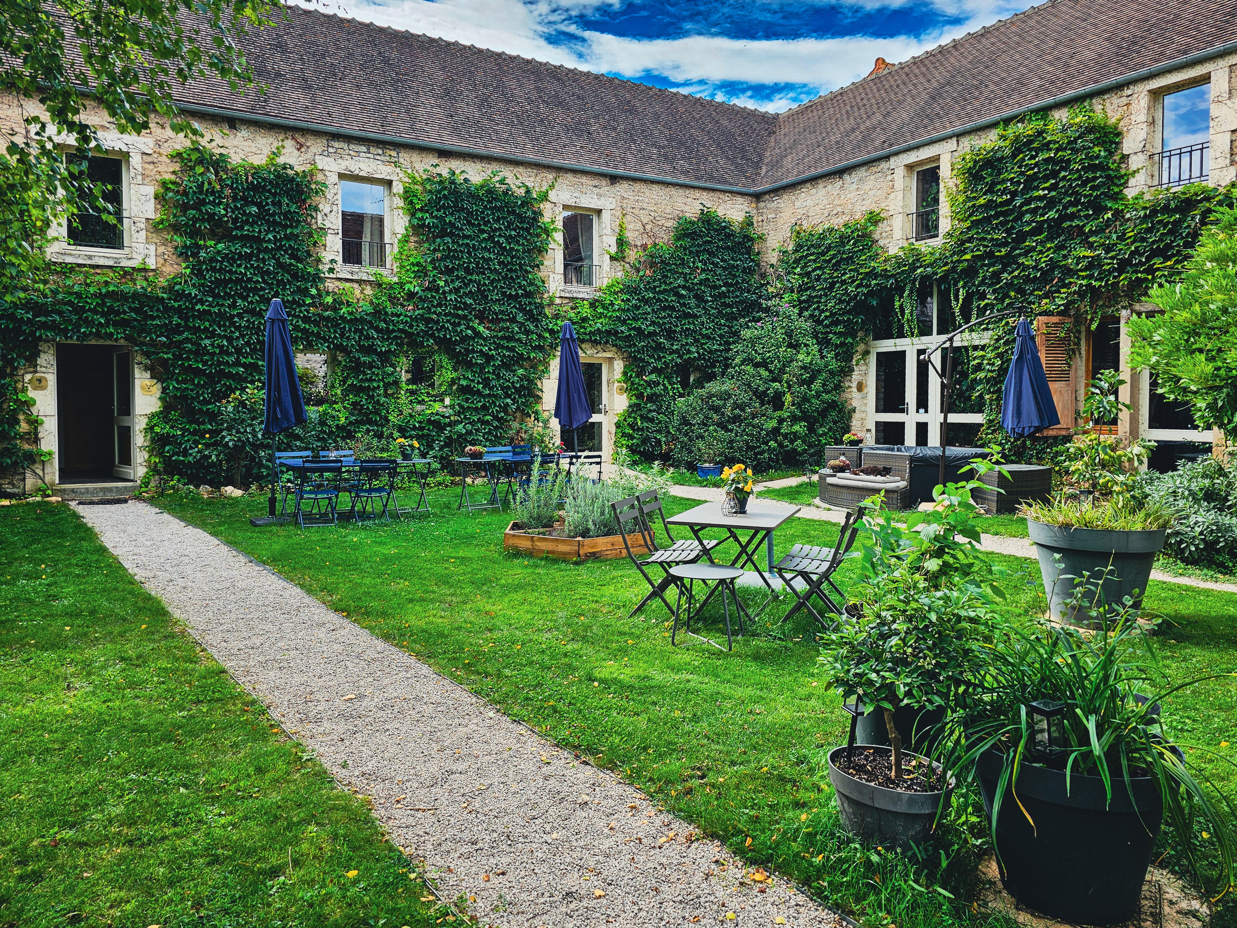 Cour avec jardin et tables extérieures.