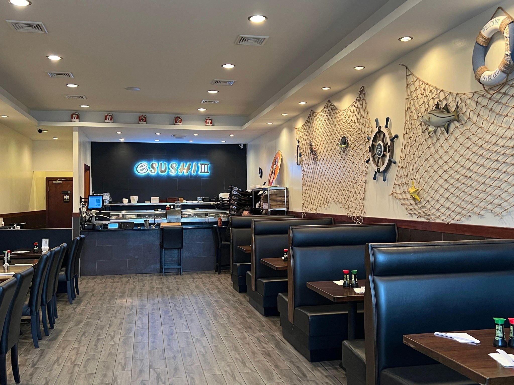 The modern interior of E Sushi III, featuring sleek wooden accents, cozy seating arrangements, and ambient lighting that creates a welcoming atmosphere for diners to enjoy authentic Japanese cuisine.