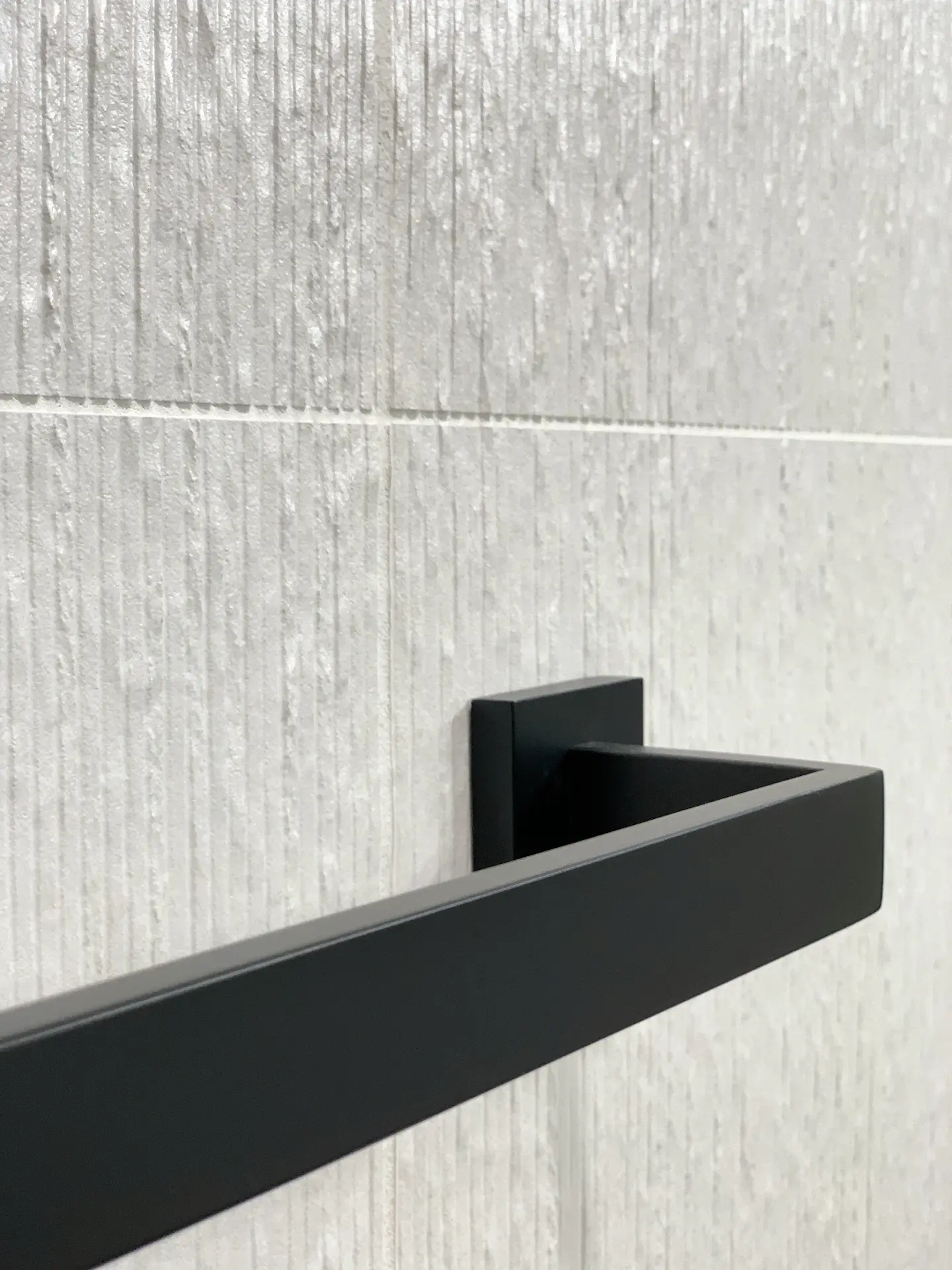 Closeup of the towel bar in the guest bathroom, featuring sleek black fixtures that complement the contemporary style of the space. Photo by Todd Huge.