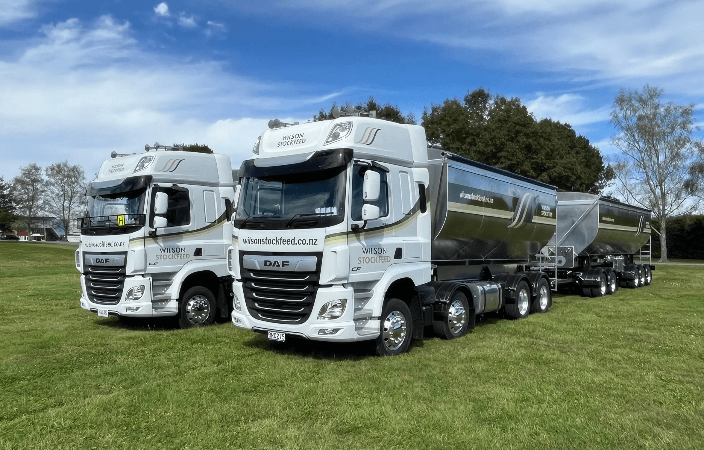 Two Wilson Stockfeed auger truck and trailer units parked on farmland