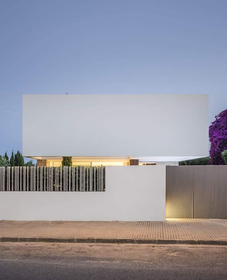 Concrete fence with timber batten and white modern house