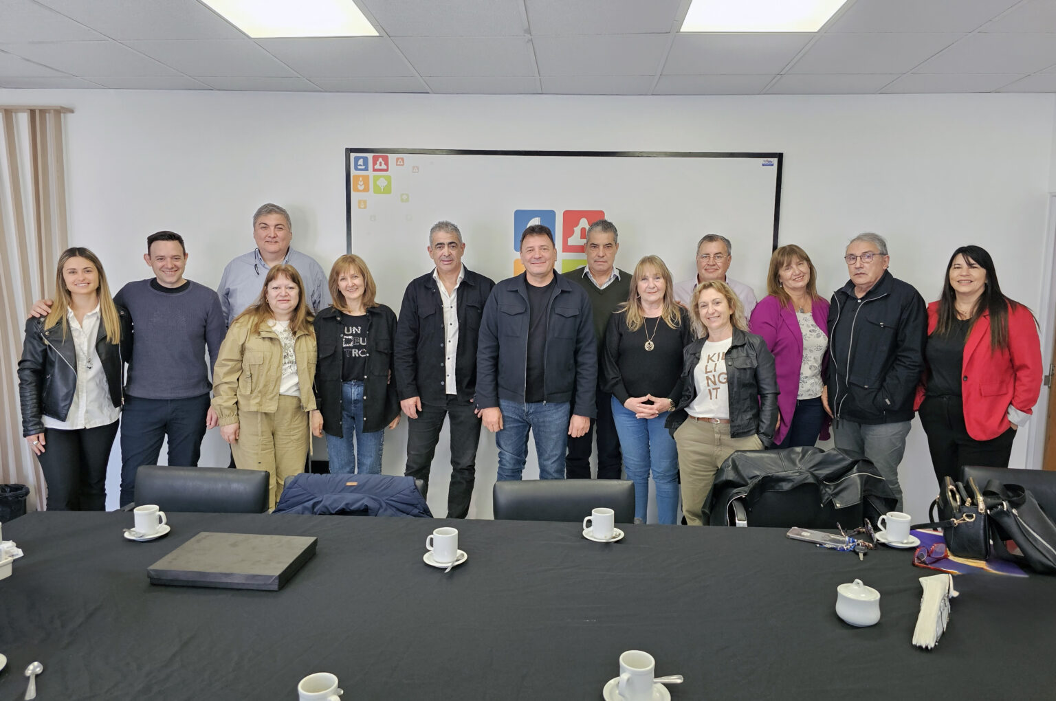 Catorce personas posan detrás de una mesa en un entorno profesional.