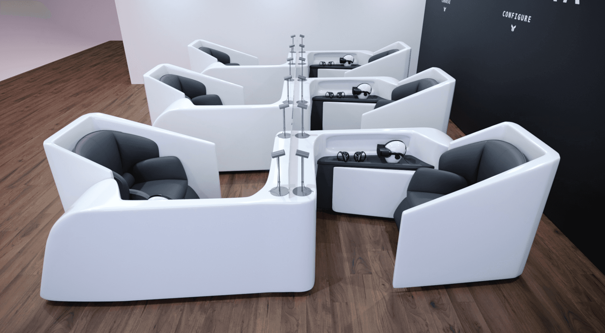 Modern, angular white seating pods with black cushions are arranged on a wooden floor in a minimalist, open space.