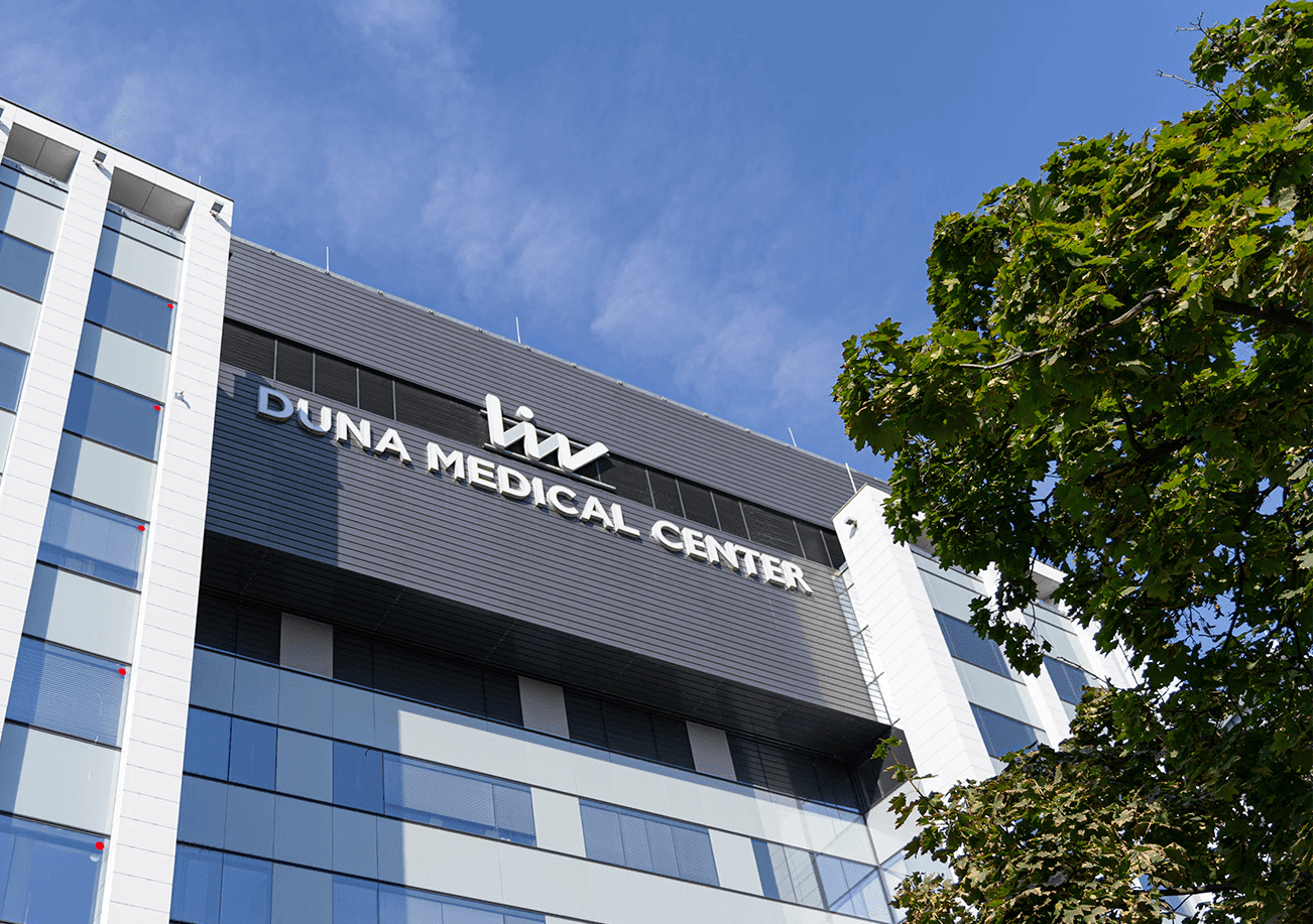  image of Imperial Dental's modern treatment room featuring blue dental equipment, a monitor with the clinic’s logo, and natural light from large windows overlooking a park.