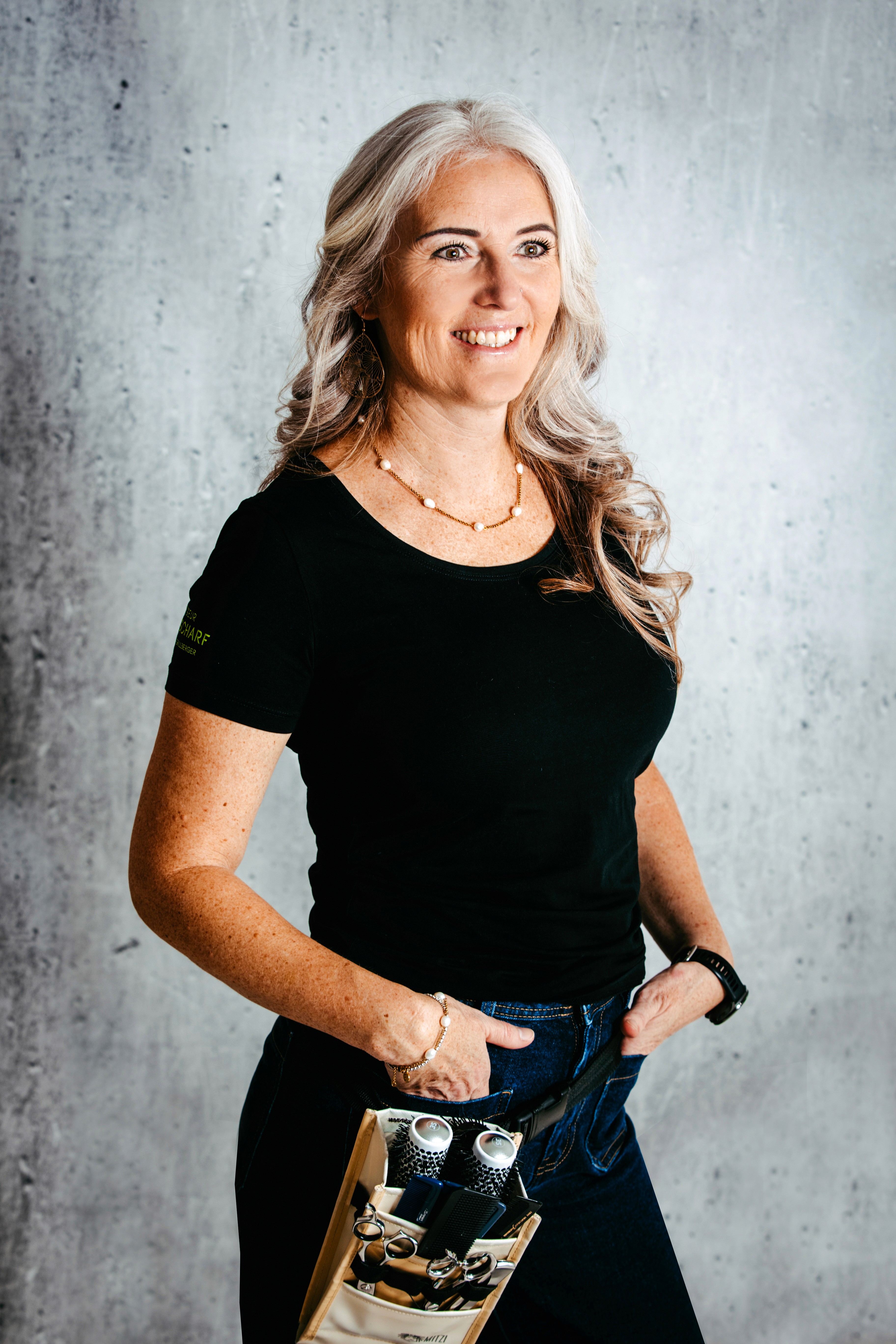 A stylist is doing a client's hair at the Camelia beauty salon. In one hand, they hold a hairdryer, and with the other hand, they adjust the hair.