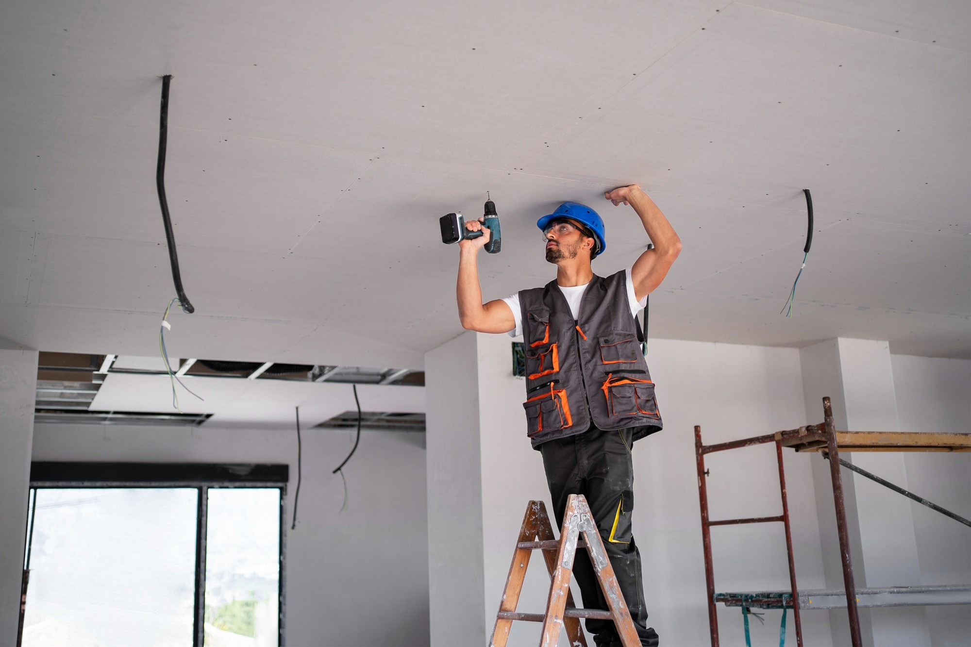 Ouvrier posant un plafond dans une maison en rénovation