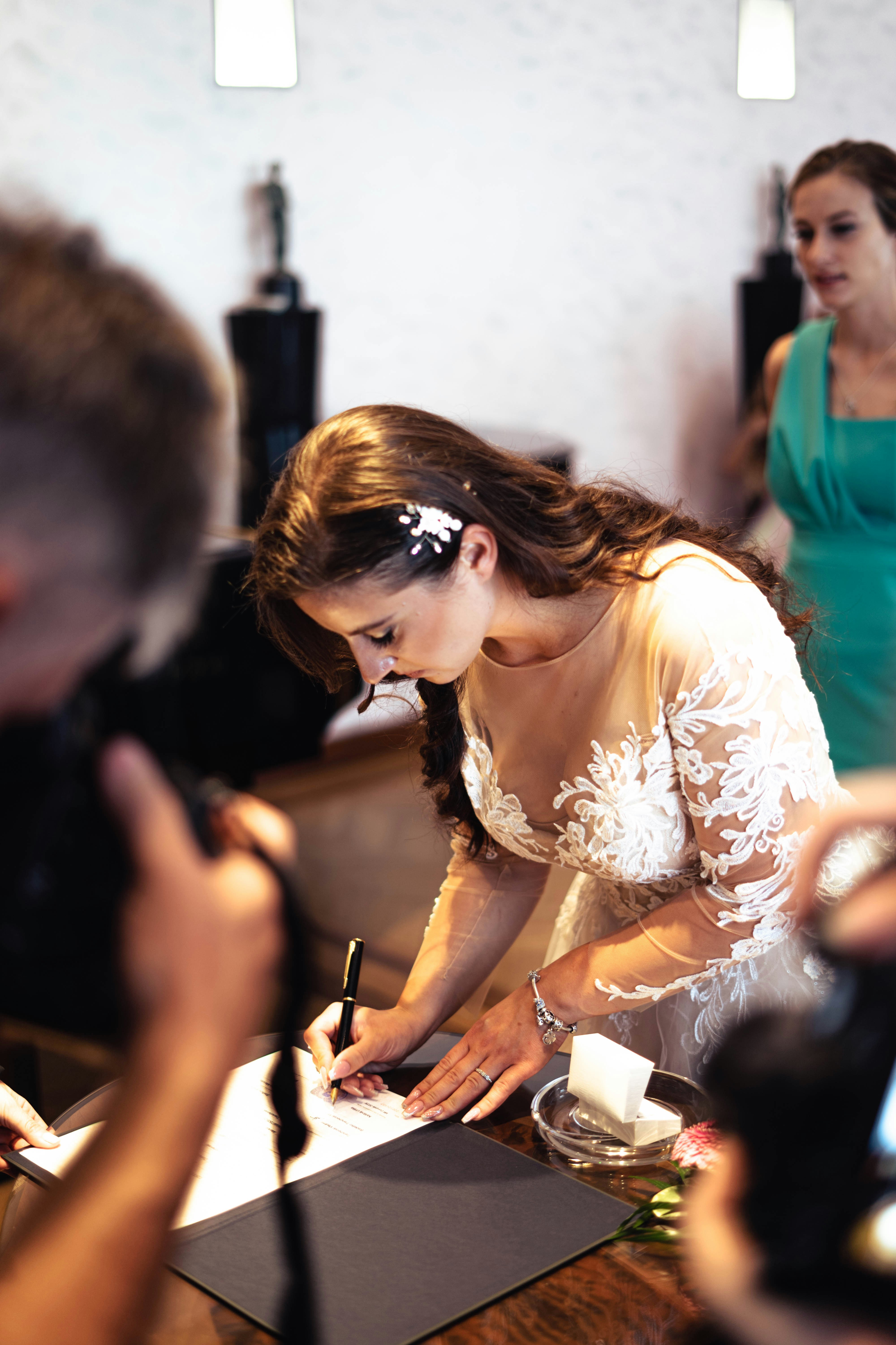 a woman in a white dress signing a piece of paper