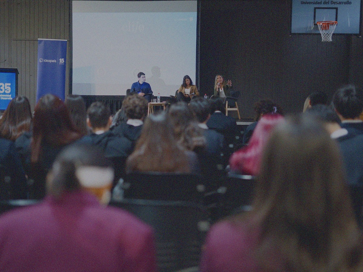 Expositores hablando en un escenario frente a alumnos en un evento realizado en la Región del Biobío por IdeaPaís.