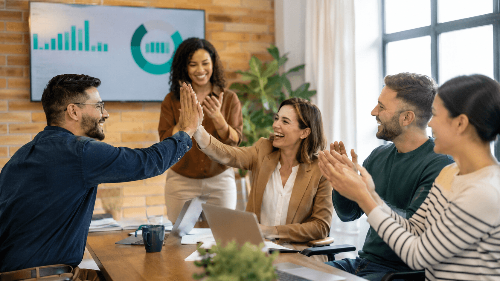 Equipe pequena comemorando o resultado de uma meta batida no ambiente de trabalho