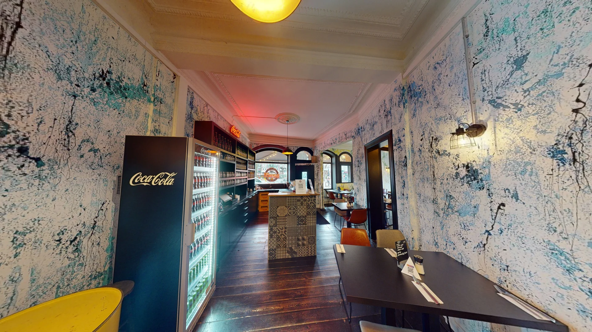 Modern interior with marble walls, wooden floors, and a bar area, illuminated by warm lighting.