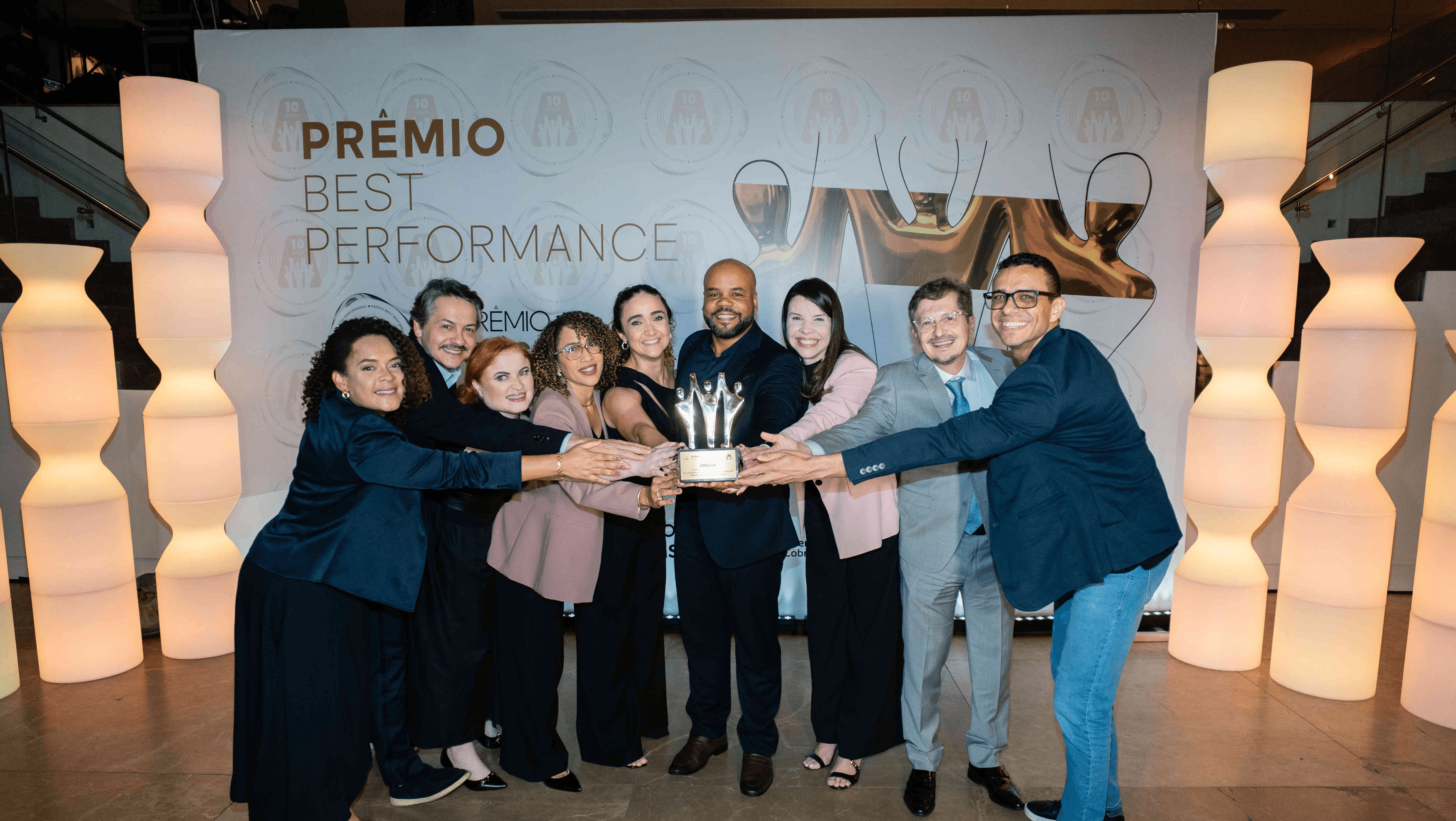 Executivos da EMBASA posando com troféu prata e certificado no palco do Prêmio Best Performance 2025