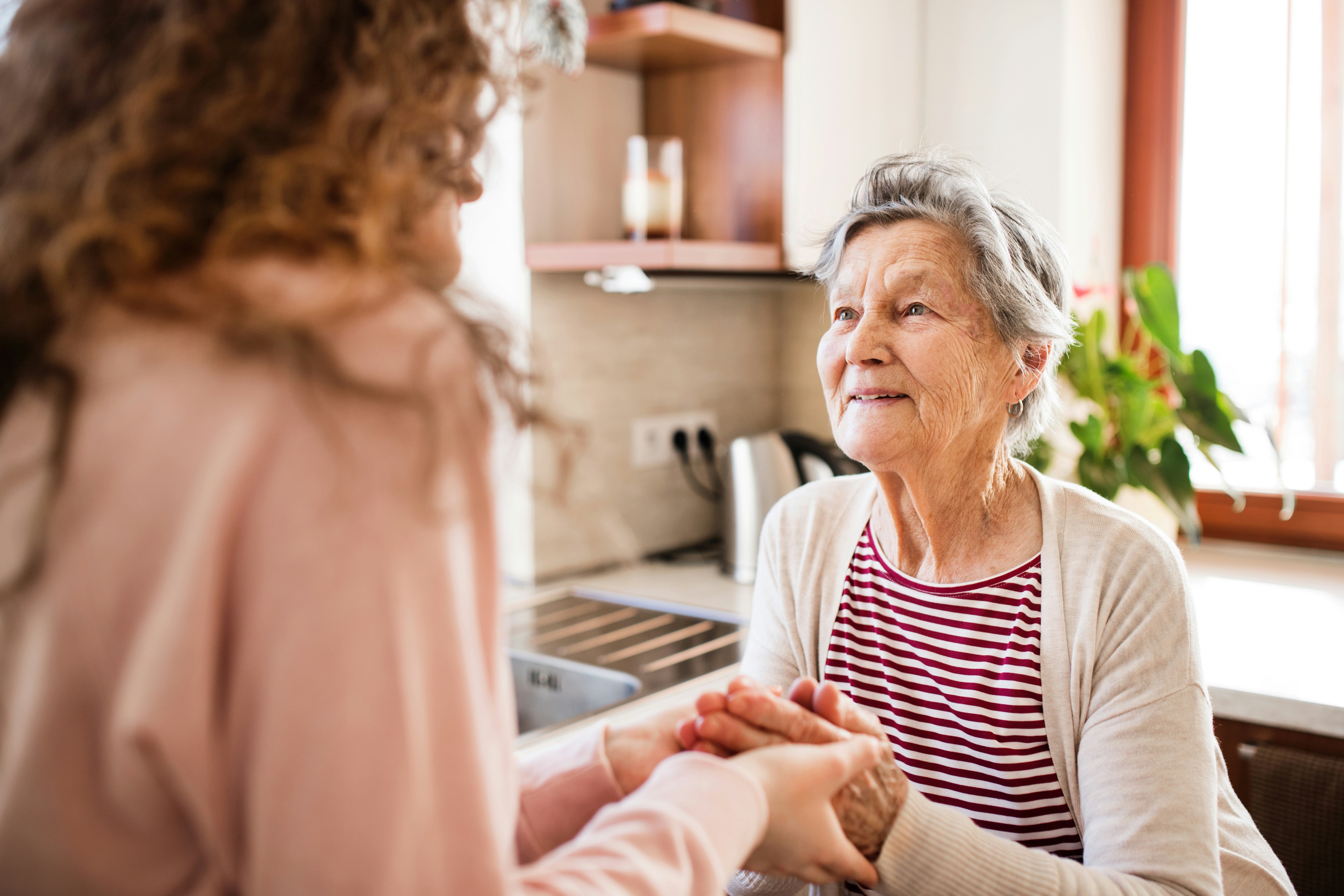An older woman smiling while holding hands with a younger woman.