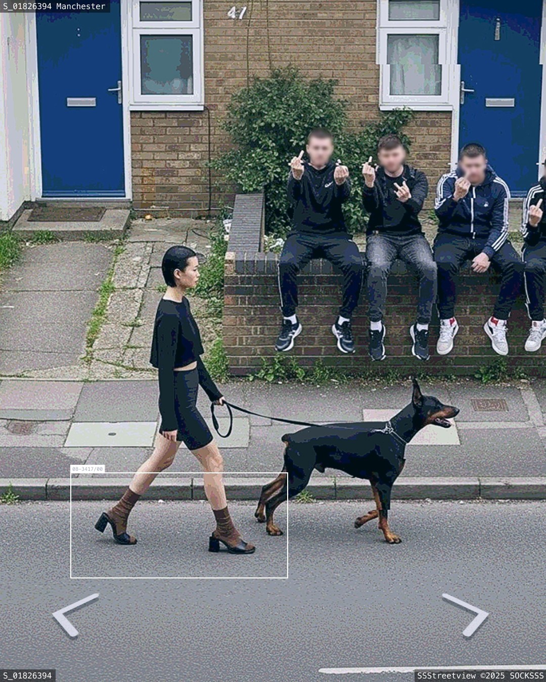 Une femme avec des chaussettes blanches marche sur le trottoir avec son chien devant des chavs anglais faisant des doigts d'honneur