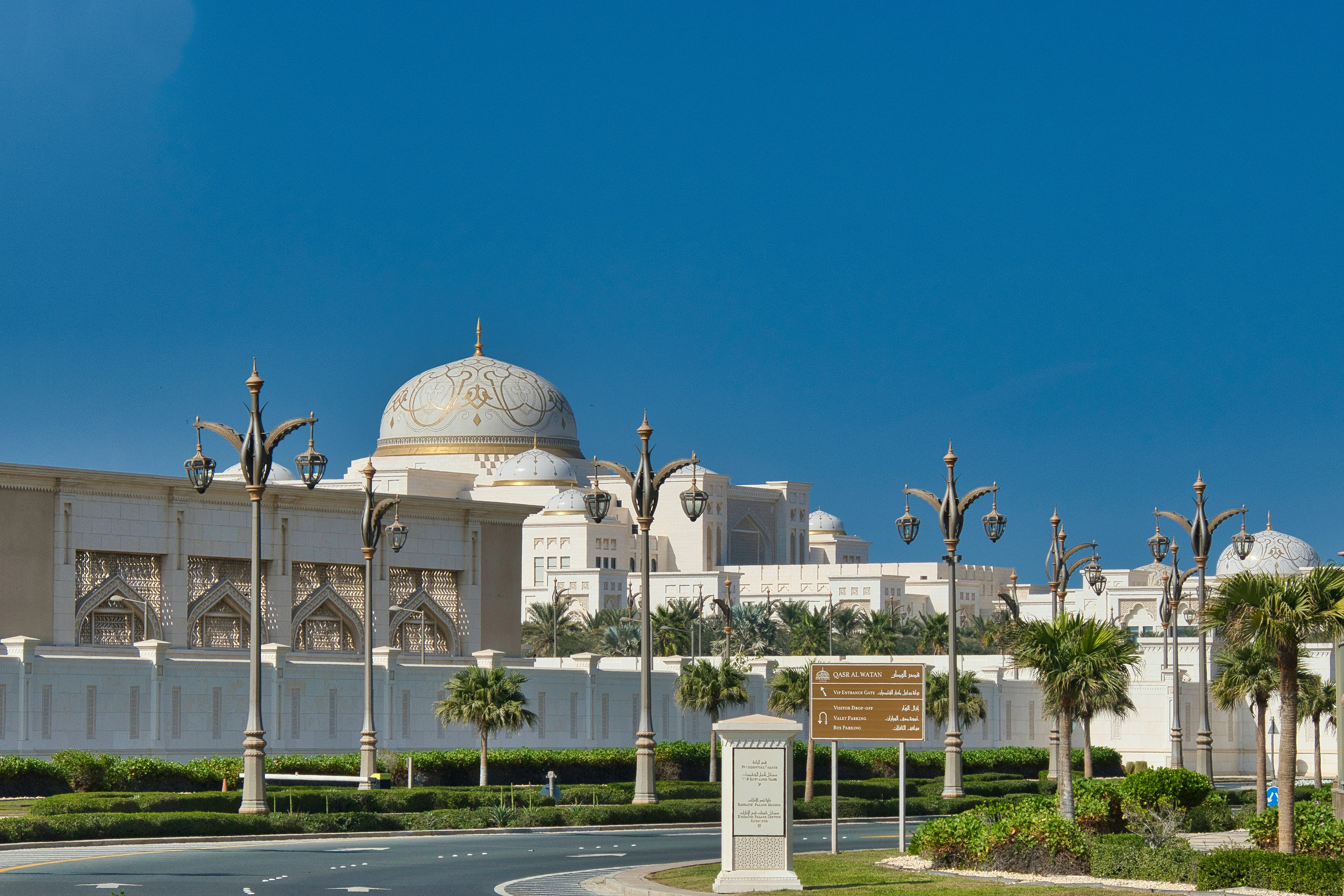 Grand building with dome and palm trees under blue sky