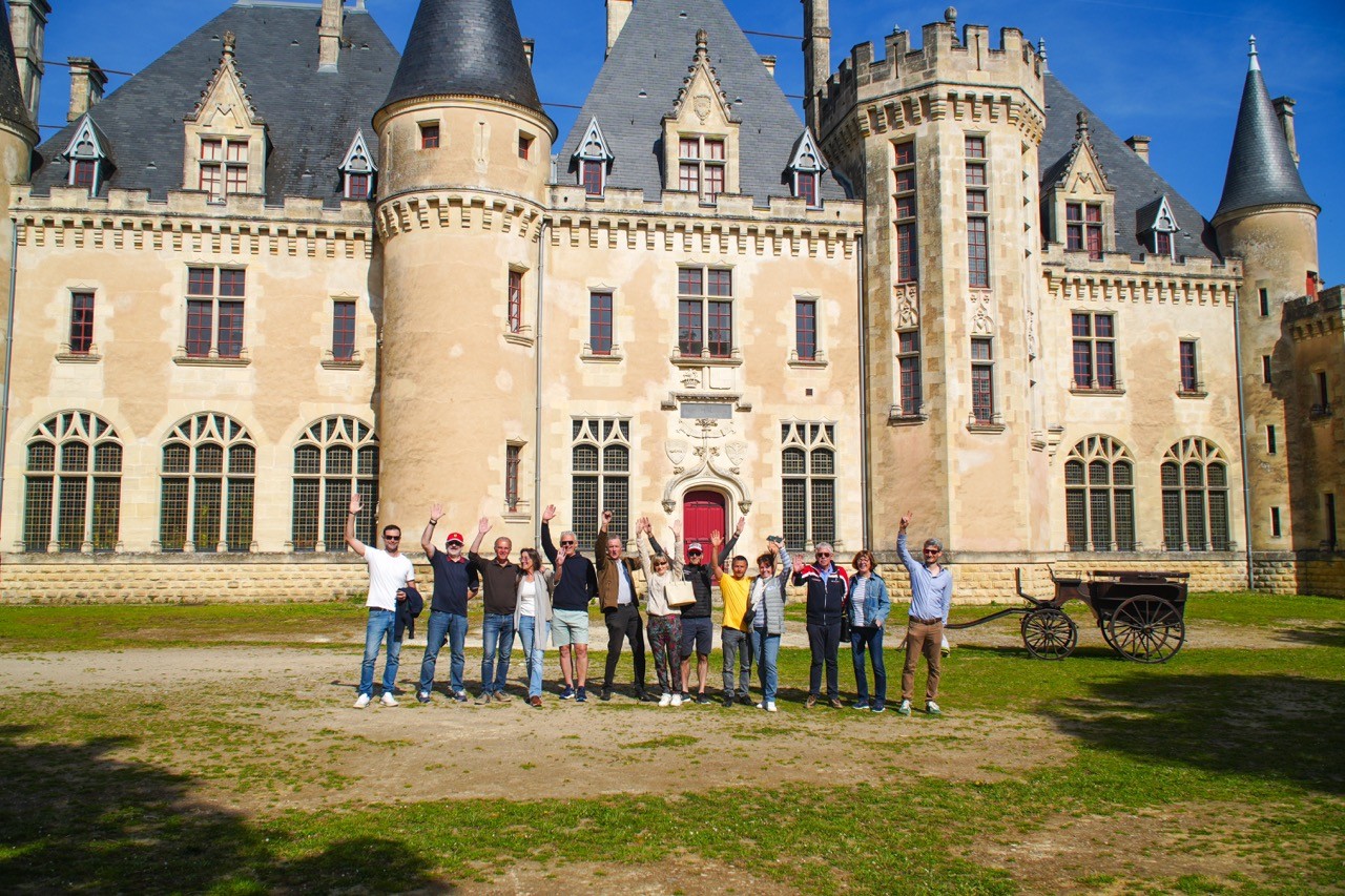 Le groupe pose bras levés devant un château à tourelles, road trip Auvergne Périgord