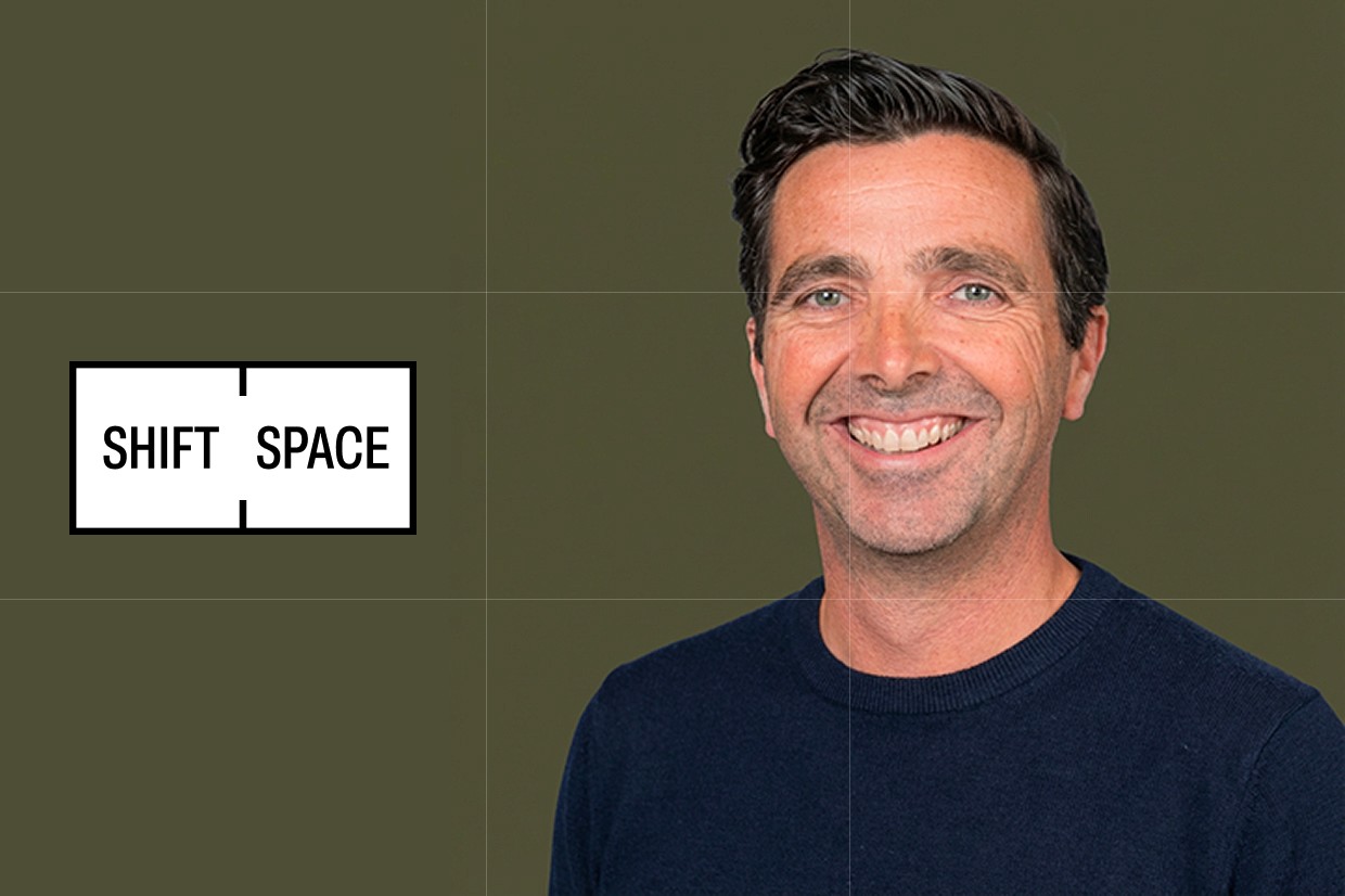 portrait of a male wearing a dark blue sweater on a dark green background